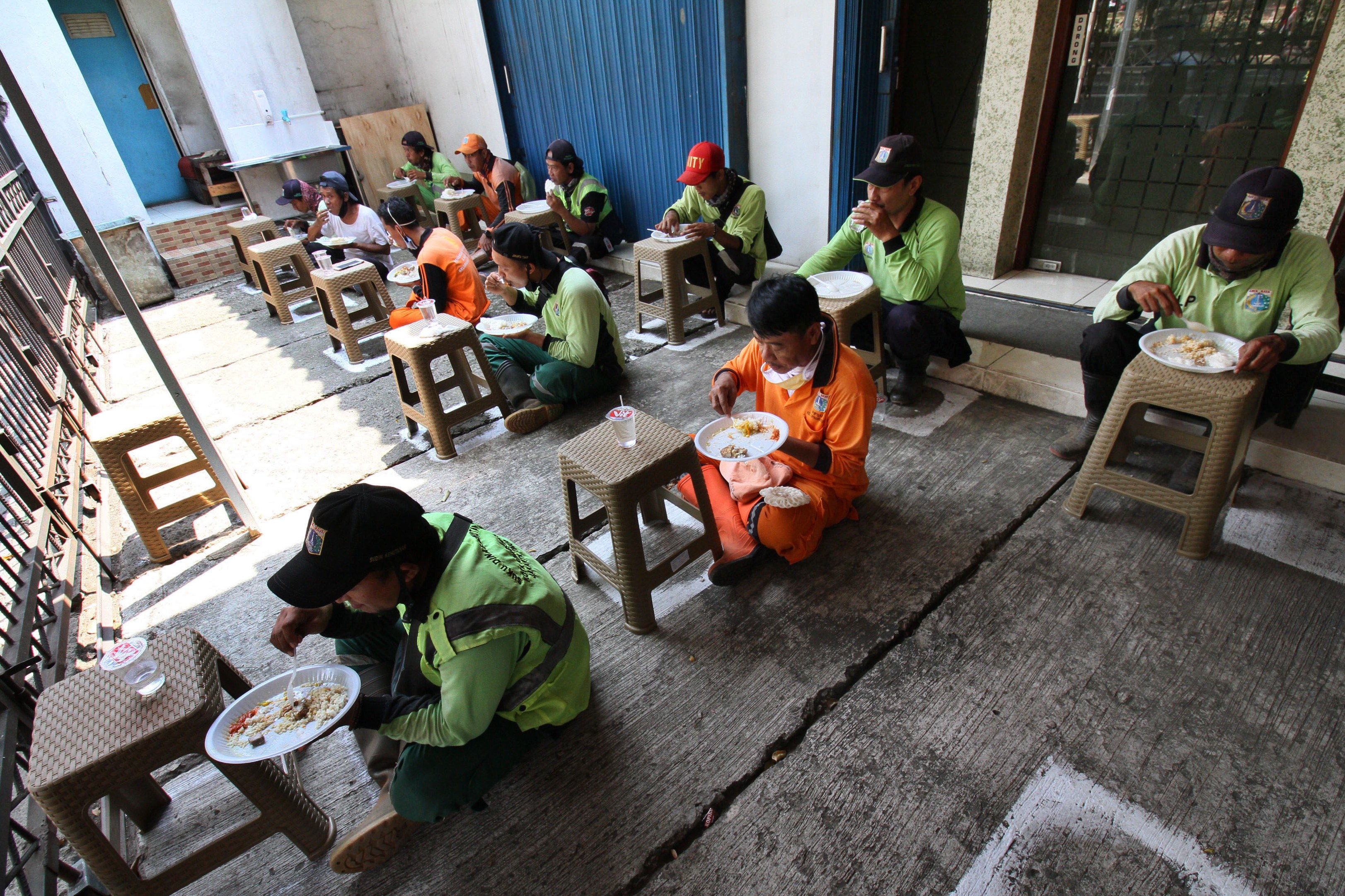Warga makan siang gratis dengan tetap menjaga jarak di Jalan Basuki Rachmat, Jakarta Timur, beberapa waktu lalu.