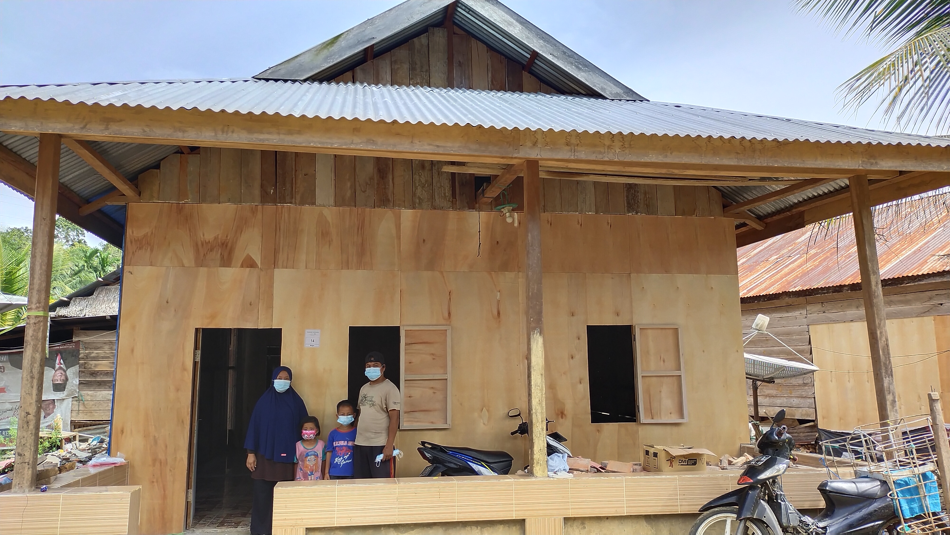 Mujar bersama keluarga di depan huntara miliknya di  di Desa Botteng Utara, Mamuju, Sulawesi Barat yang dibangun oleh Media Group Peduli.
