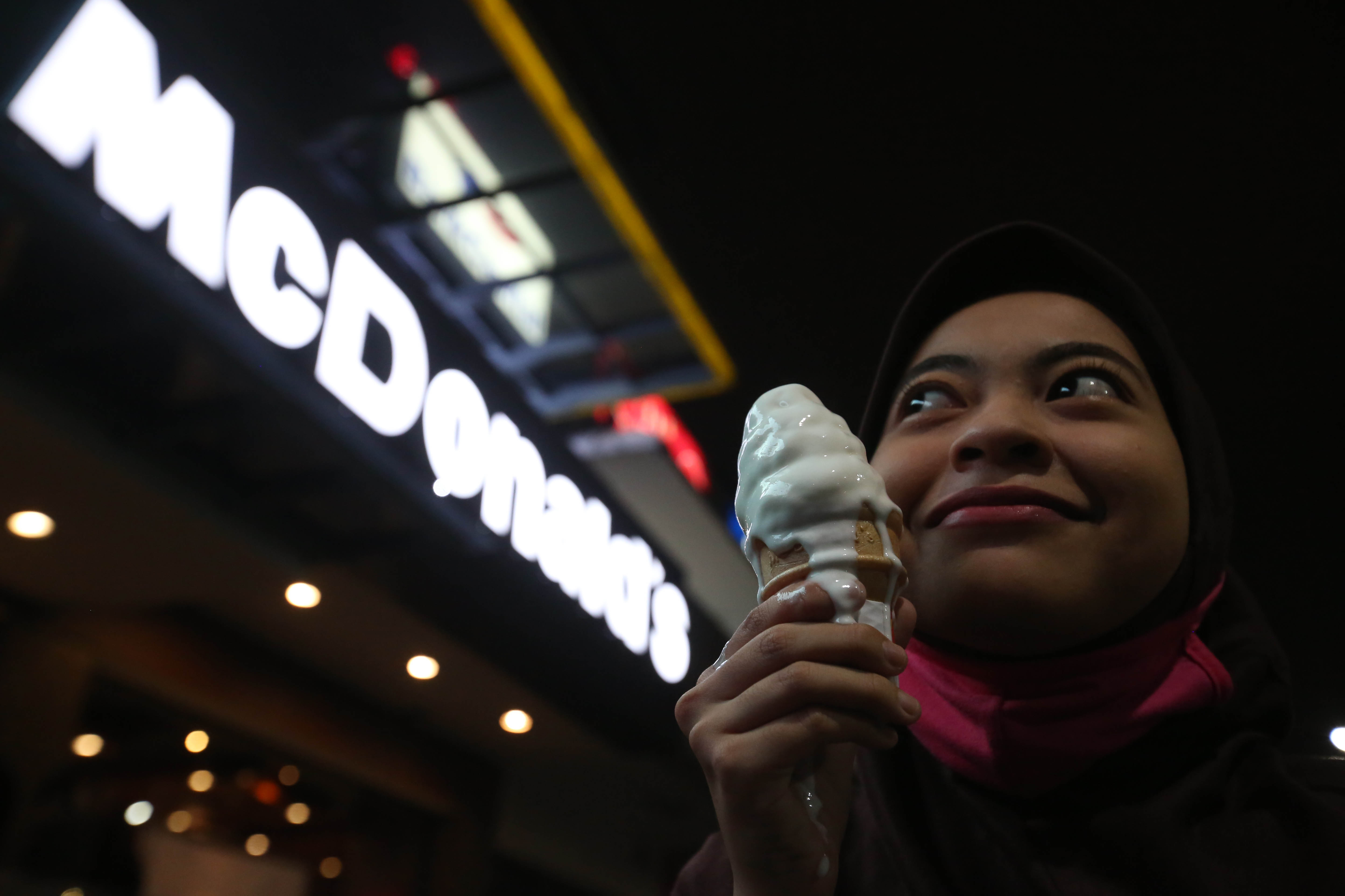 Seorang warga berfoto memegang es krim di depan logo McDonald's Jakarta.