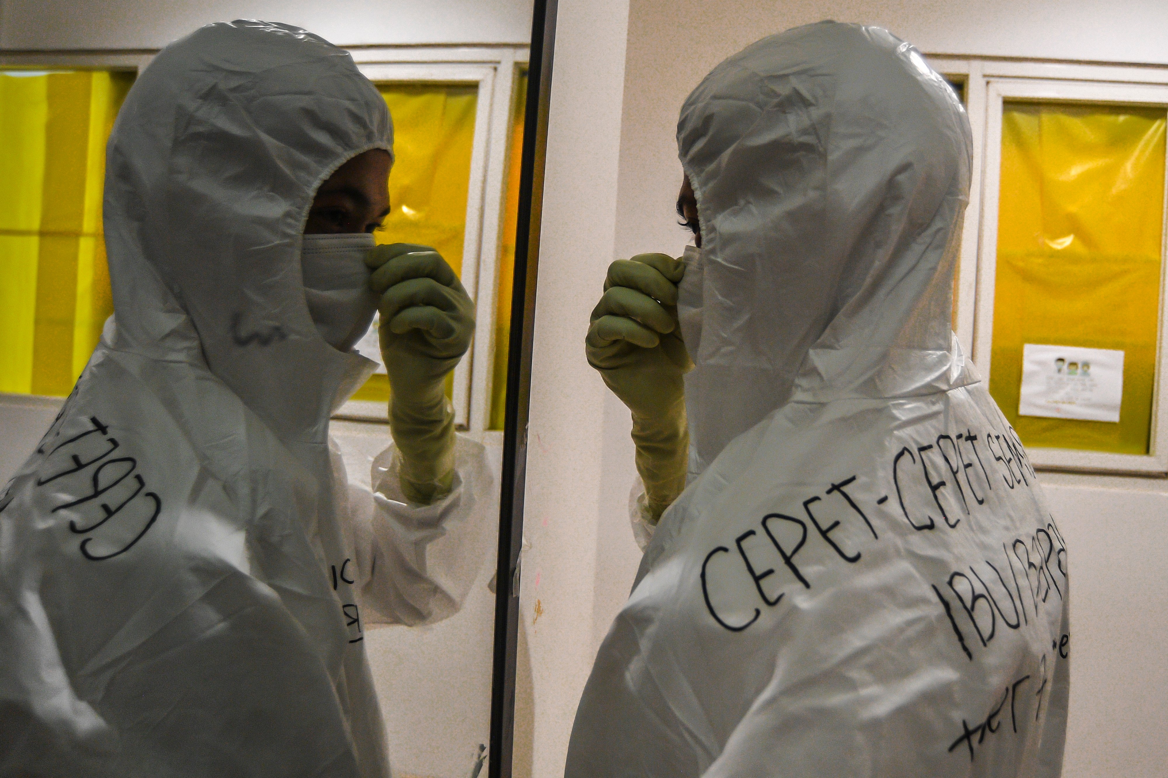 Seorang tenaga kesehatan merapikan APD saat menunggu giliran bertugas di Rumah Sakit Darurat COVID-19 Wisma Atlet, Kemayoran, Jakarta.