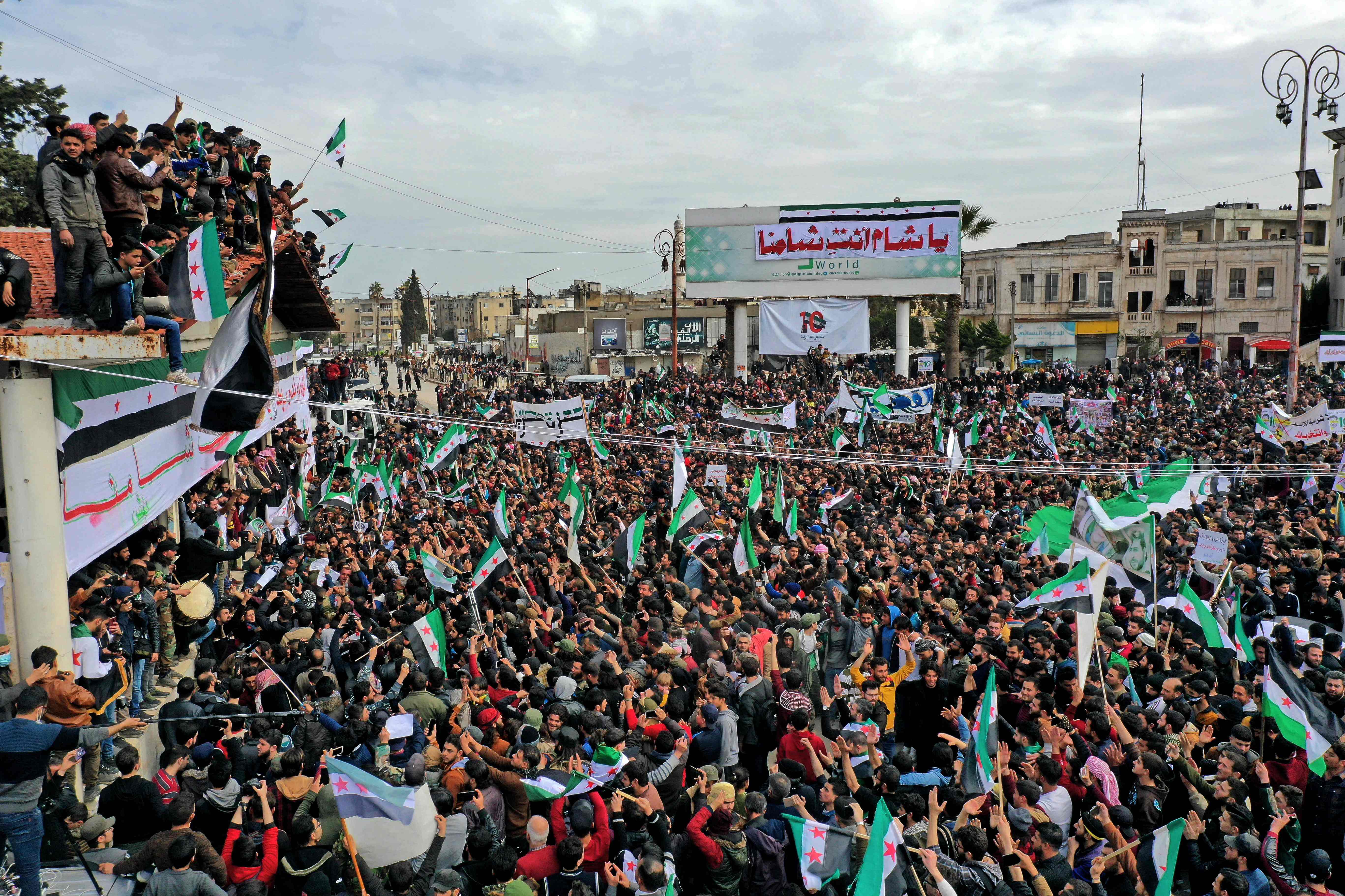 Gambar udara menunjukkan warga Suriah mengibarkan bendera nasional selama pertemuan di kota Idlib yang dikuasai pemberontak, Senin (15/3).