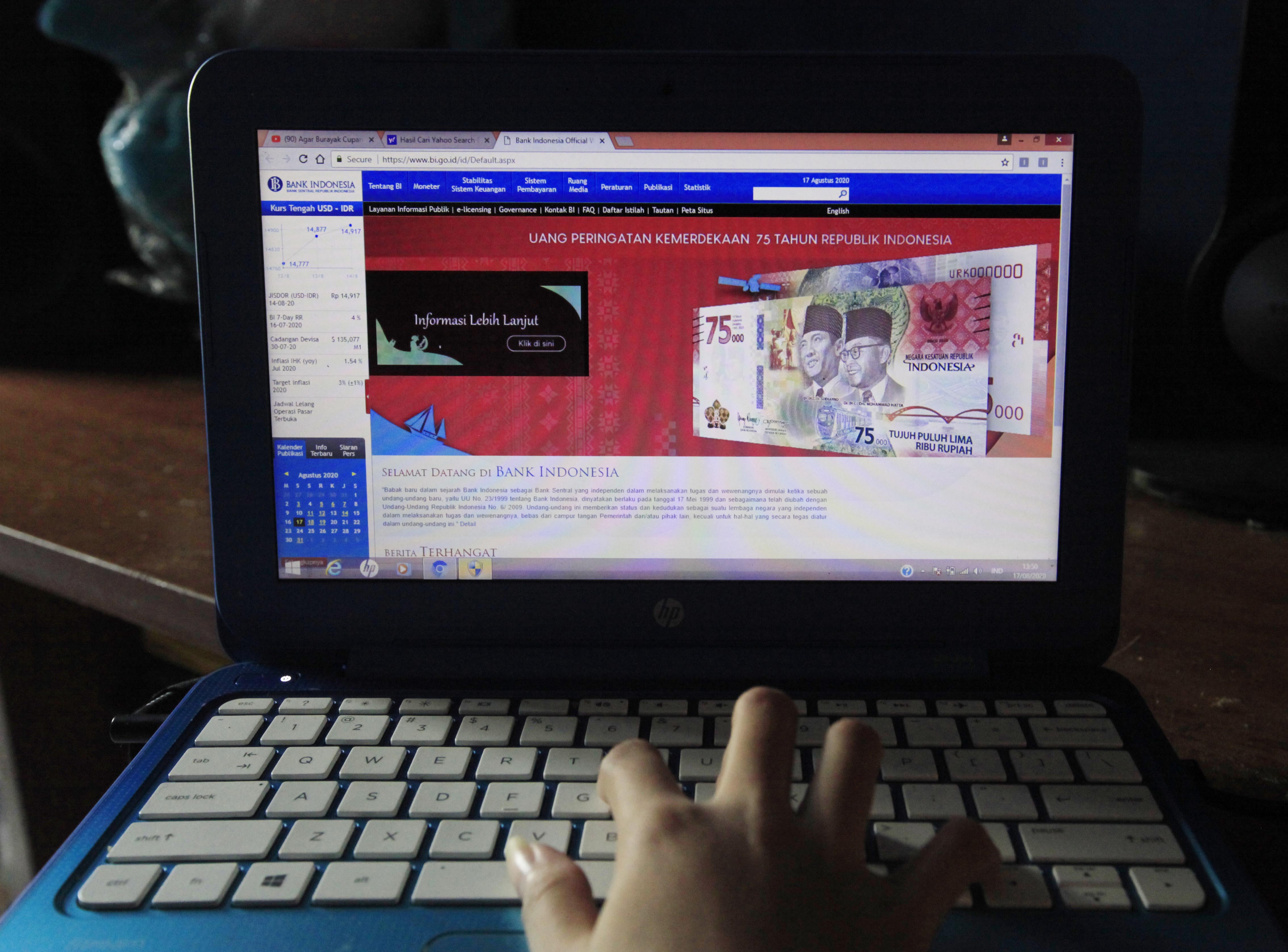 Warga melihat mata uang Rp75 ribu di laptopnya.