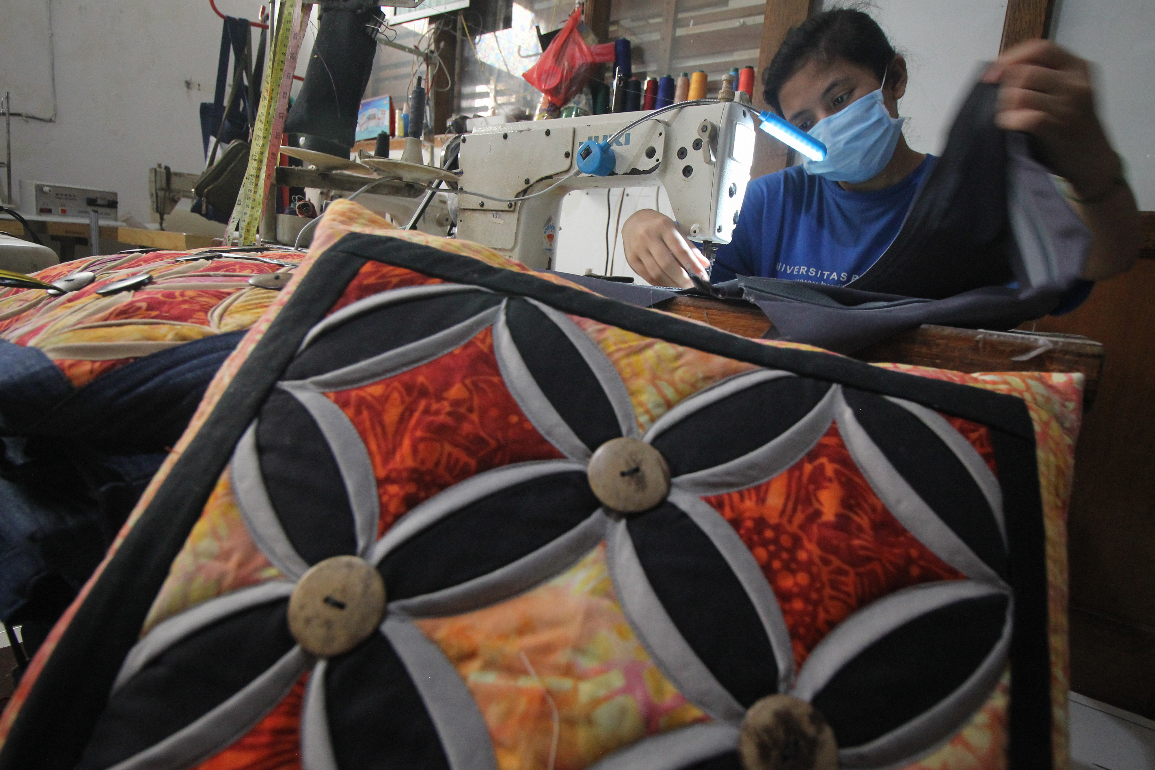 Pekerja membuat sarung bantal di Tiara Handicraft di Surabaya, Jawa Timur.
