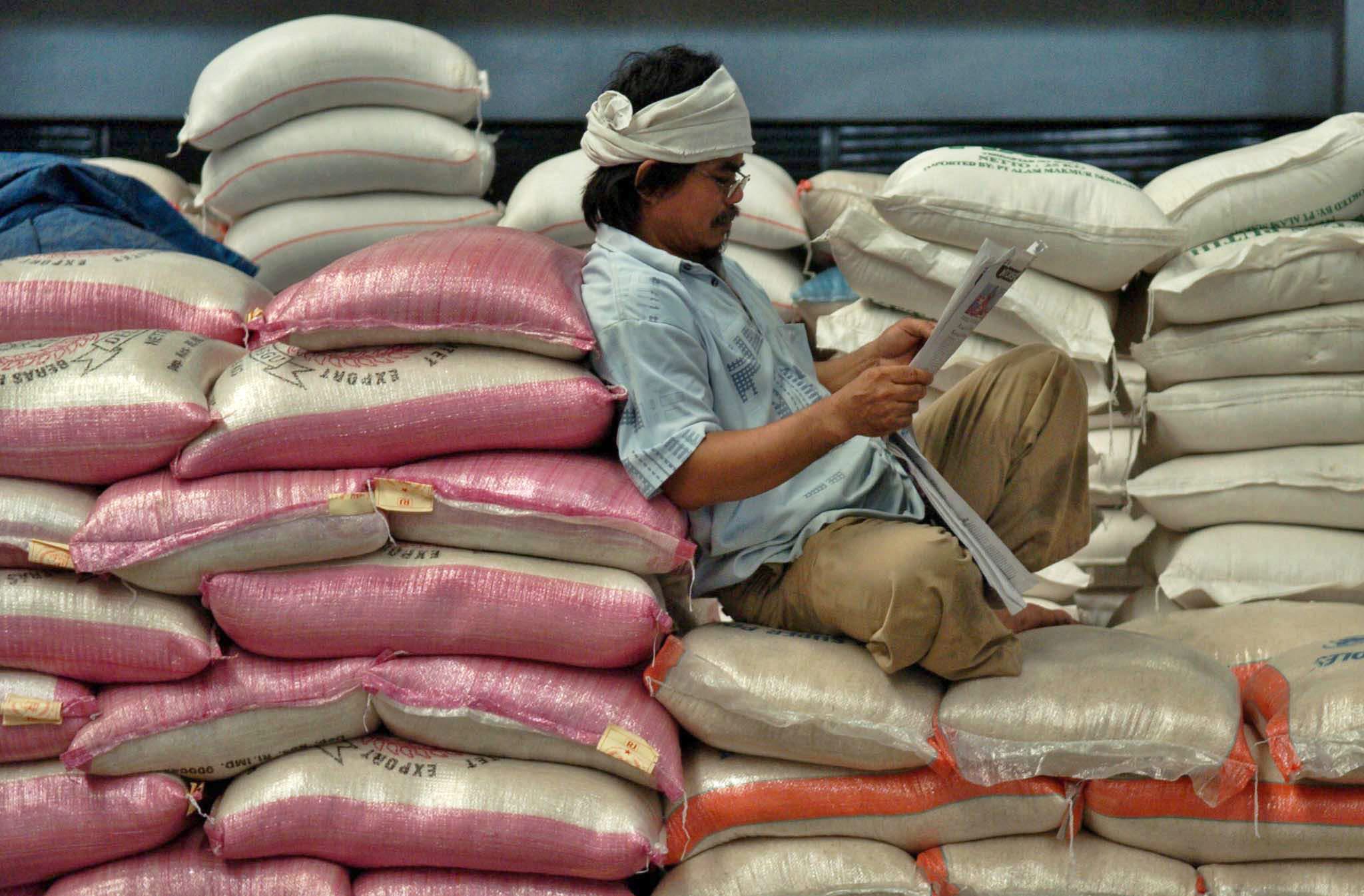  Pekerja beristirahat sambil membaca koran di atas tumpukan karung berisi beras, di pusat perdagangan beras Pasar Dargo Semarang.
