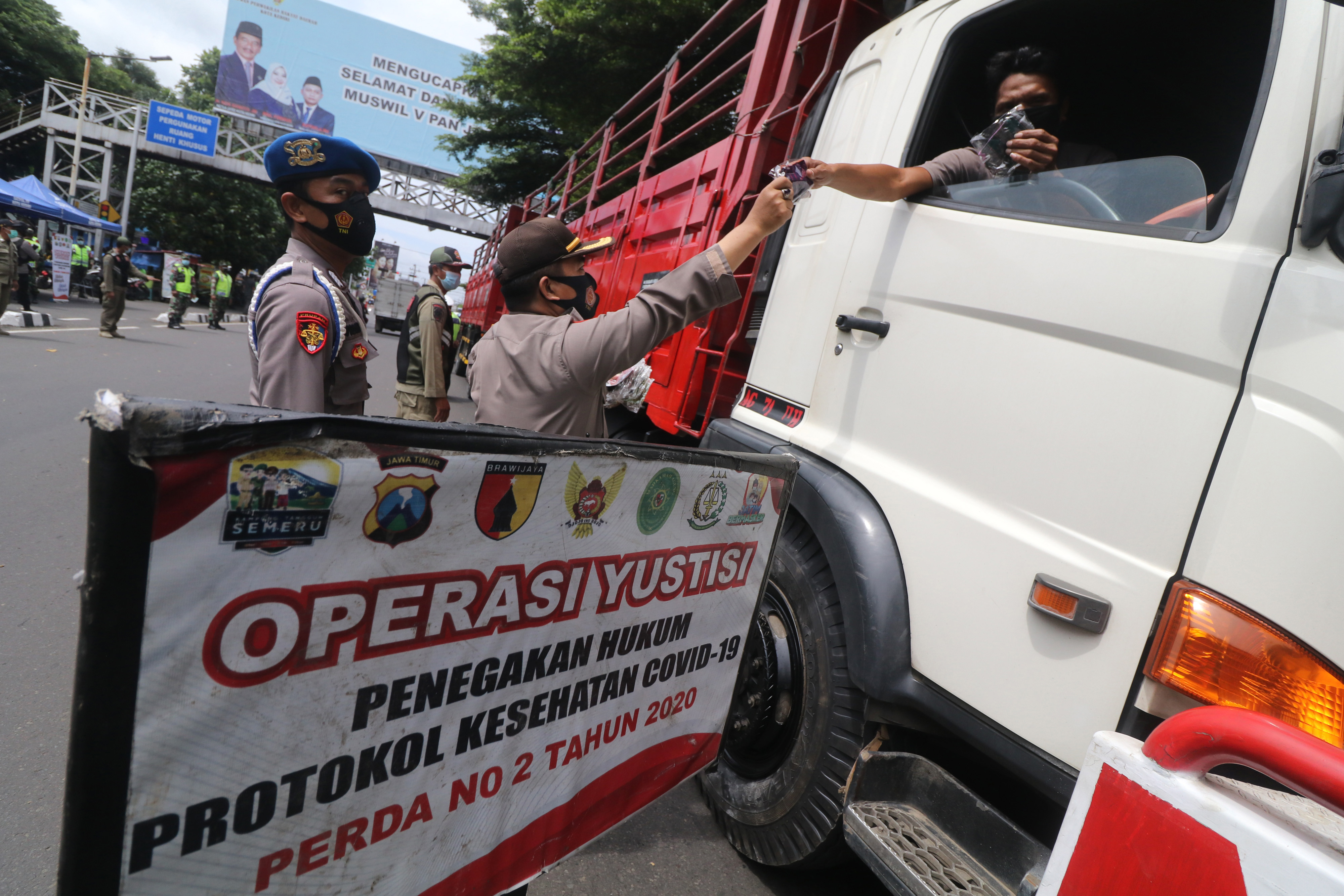 Petugas membagikan masker kepada pengguna jalan saat razia penerapan protokol kesehatan COVID-19