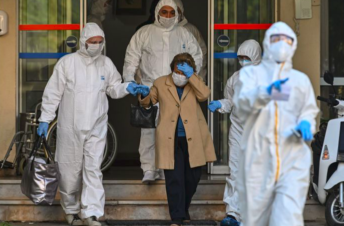 Paramedis Turki yang mengenakan pakaian pelindung membantu pasien yang menunjukkan gejala covid-19 ke ambulans.