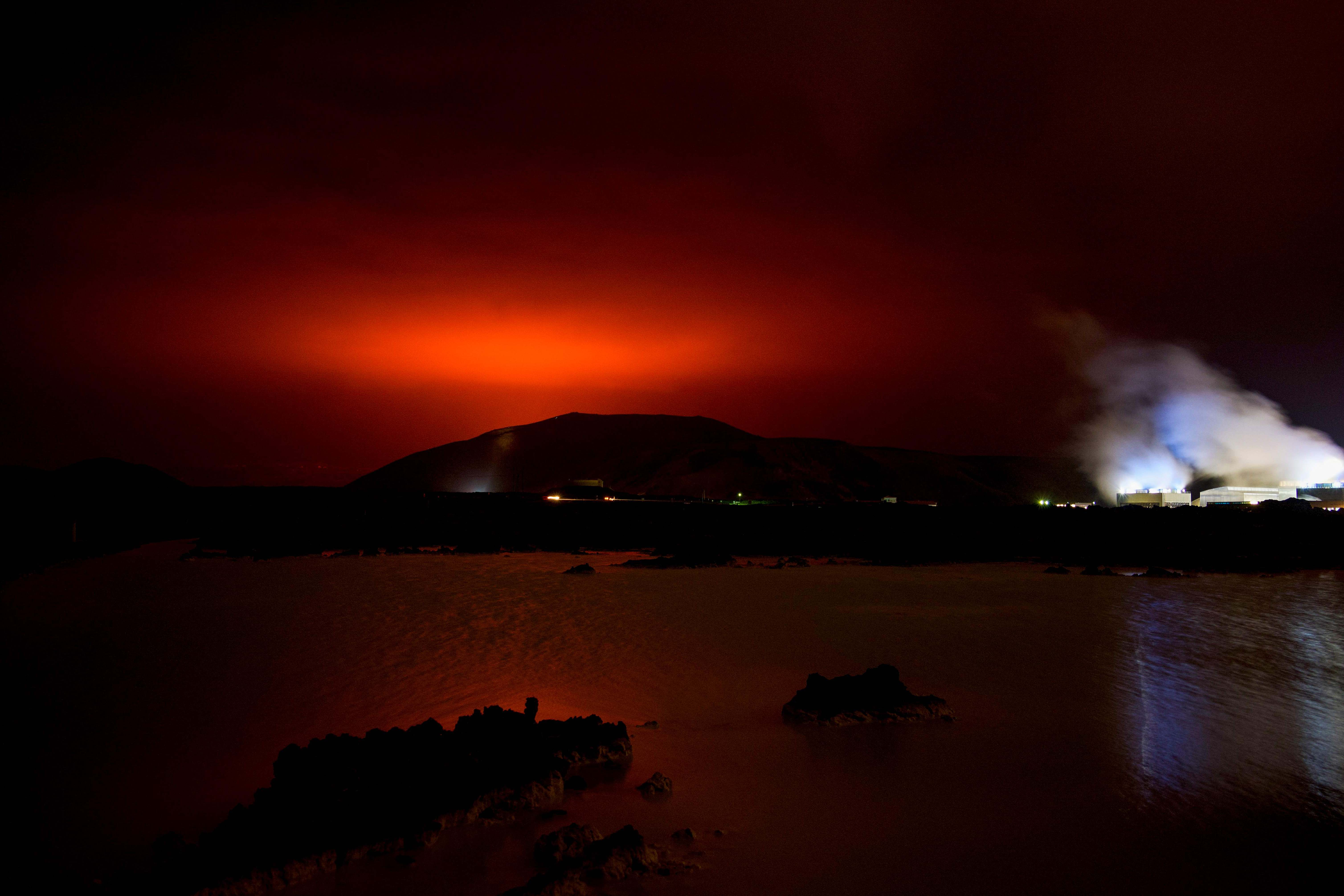 Kilau merah dari magma mengalir keluar dari gunung berapi Fagradalsfjall yang meletus di belakang Blue Lagoon yang terkenal.