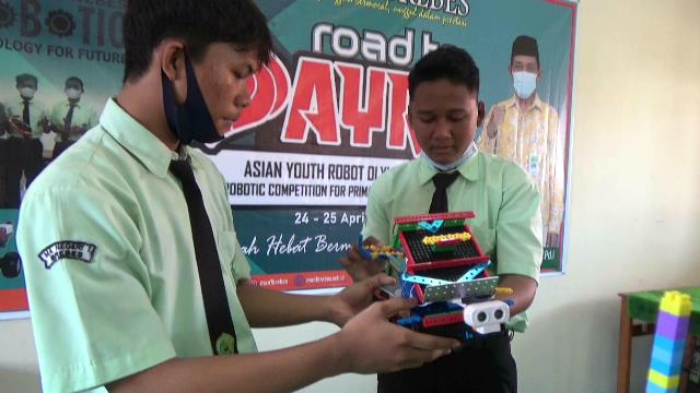 Santri MAN 1 Brebes M. Haidar Hamzah (memegang robot) dibantu rekannya. 