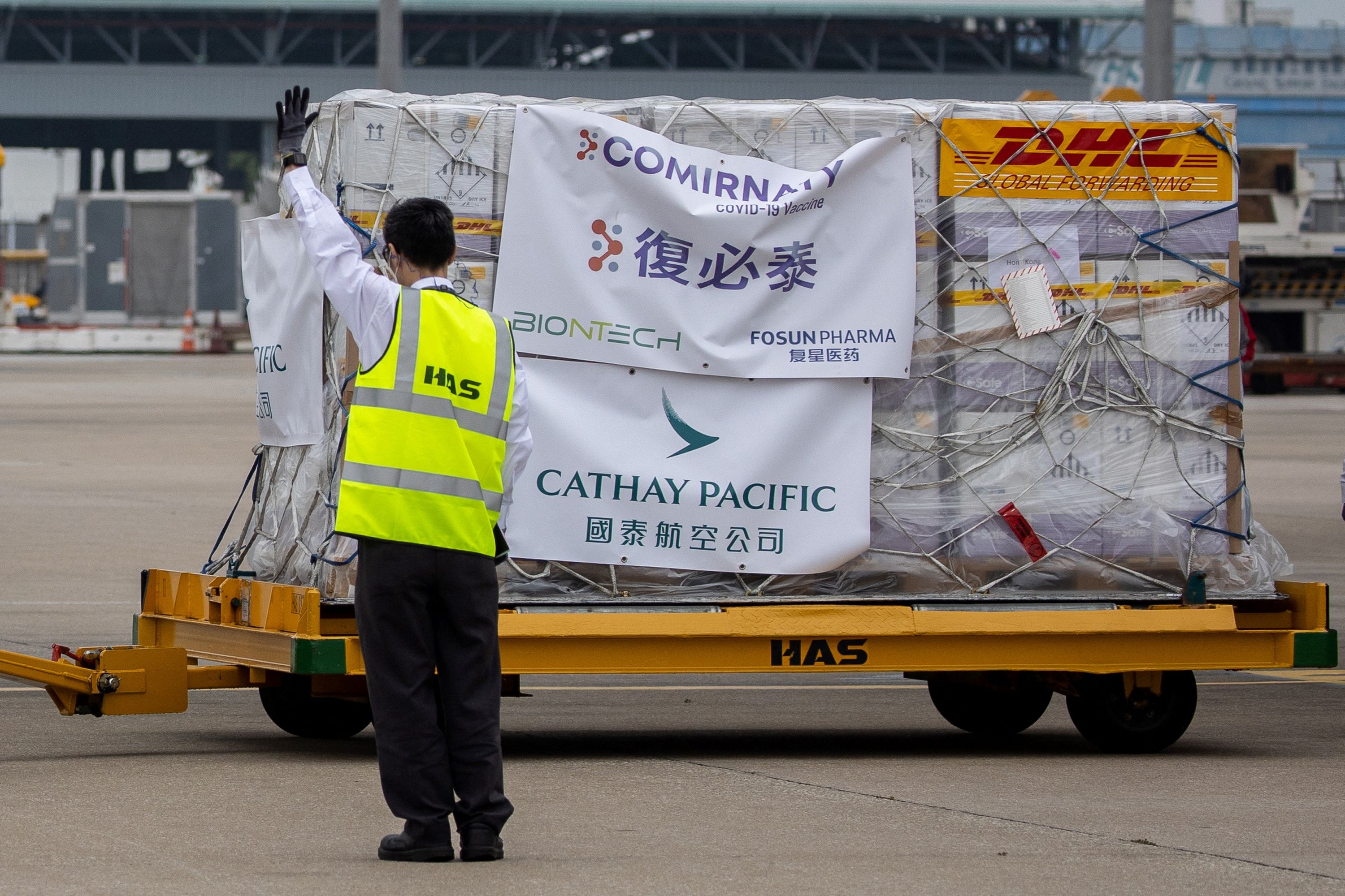 Petugas mengarahkan troli vaksin covid-19 yang tiba di Hong Kong.