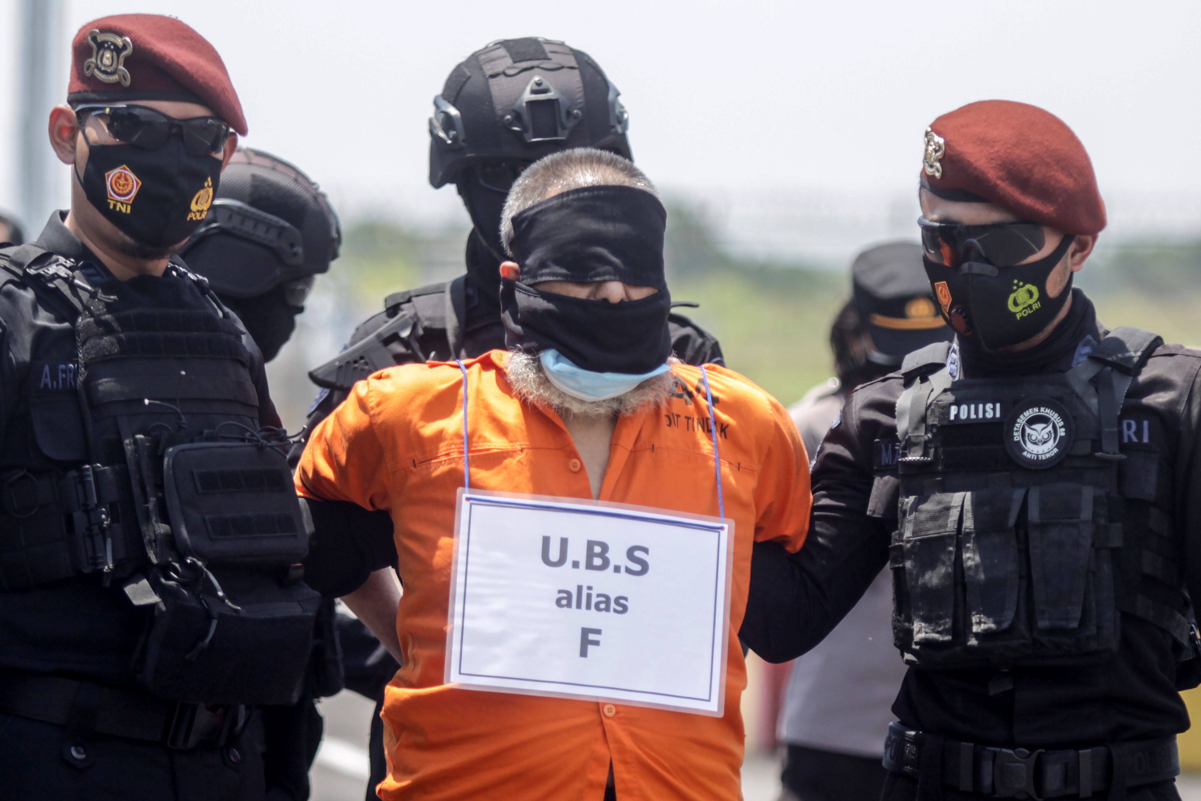 Personel Densus 88 Anti Teror membawa terduga teroris menuju ke pesawat udara di Bandara Internasional Juanda