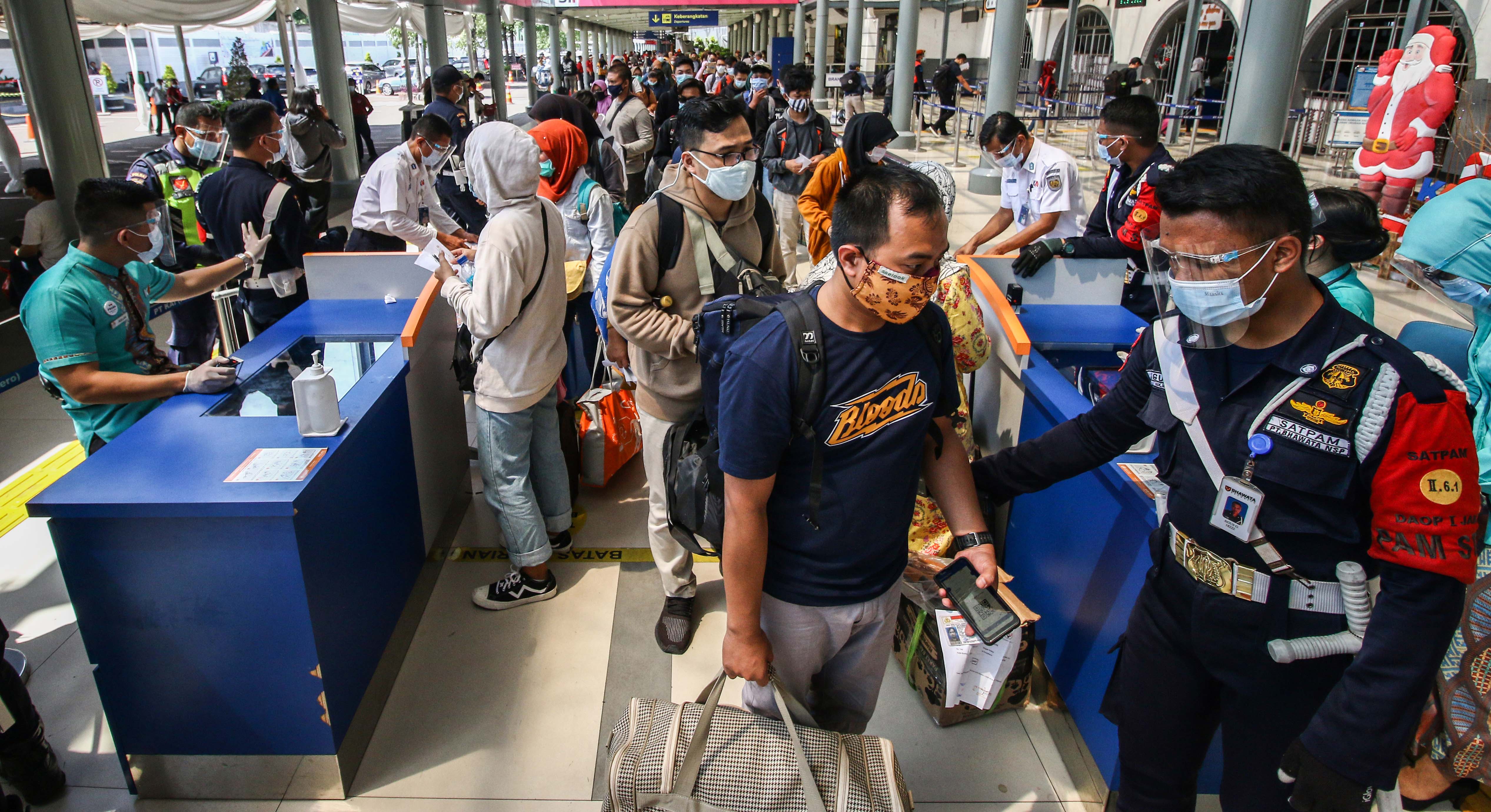Penumpang antre untuk memasuki area peron di memasuki Stasiun Pasar Senen, Jakarta, Jumat (25/12/2020).