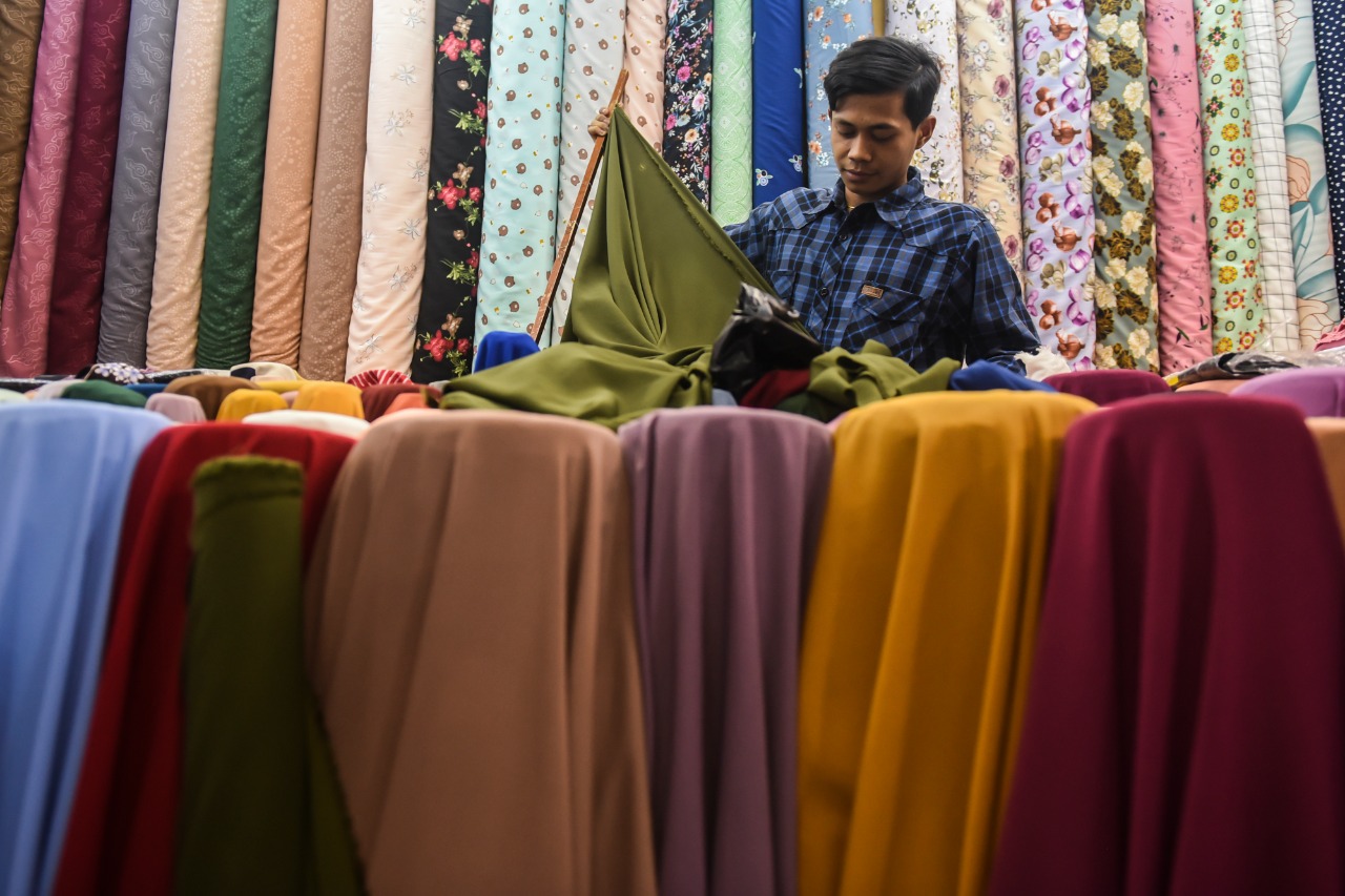 Seorang penjual tekstil tengah membereskan dagangannya.