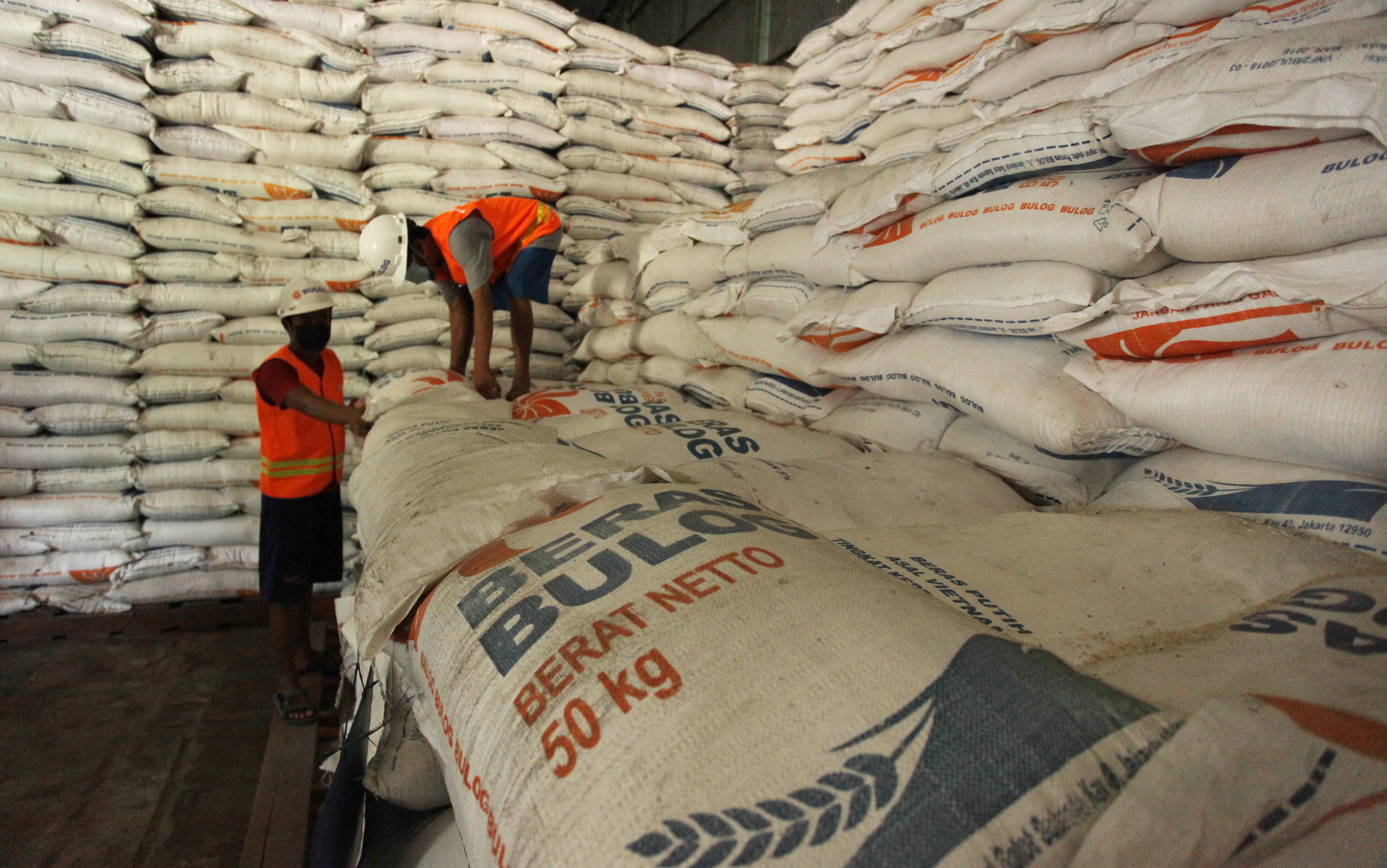 Pekerja menata karung berisi beras di gudang milik Perum Bulog.