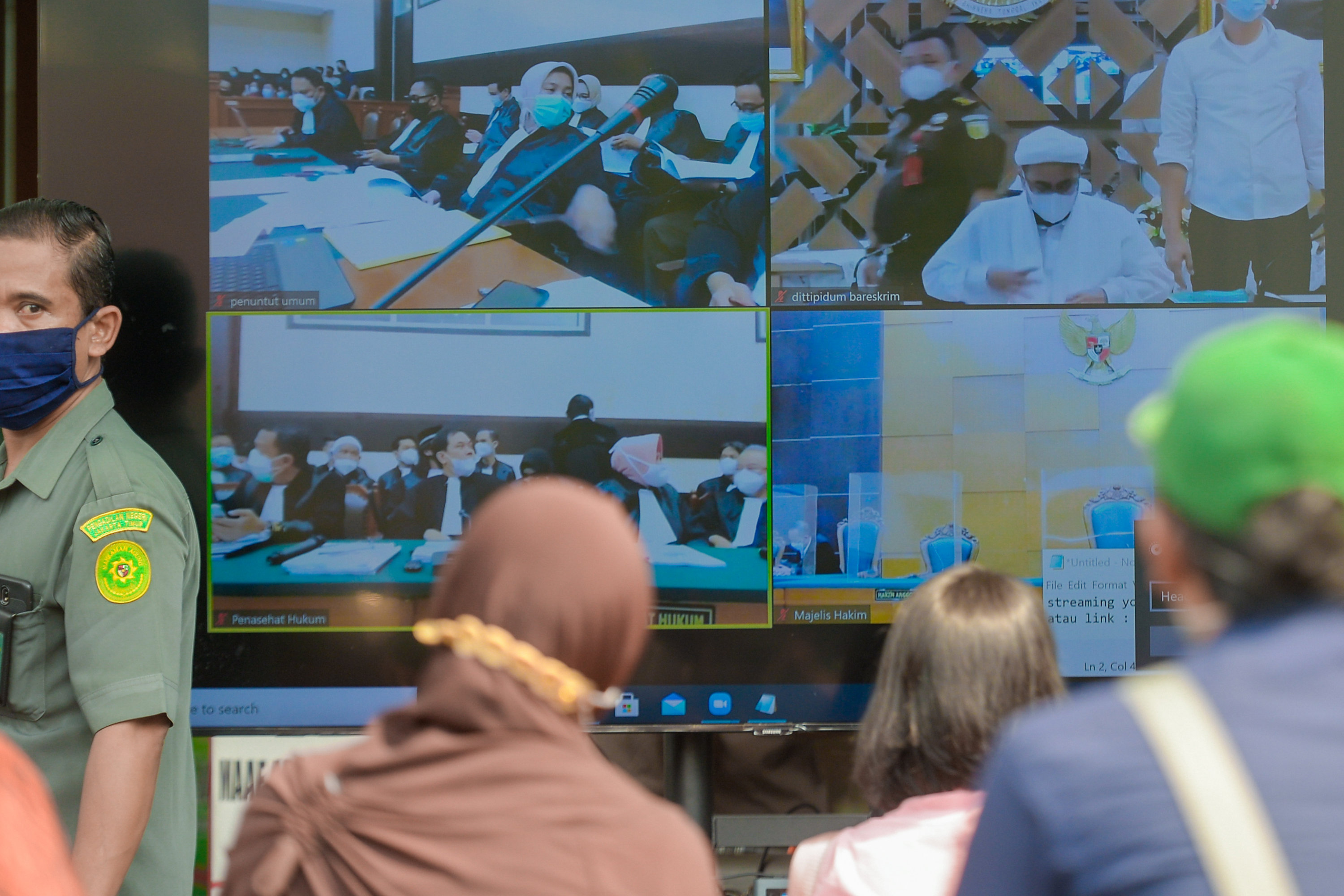 Layar menampilkan suasana sidang kasus pelanggaran protokol kesehatan dengan terdakwa Rizieq Shihab, Selasa (16/3).