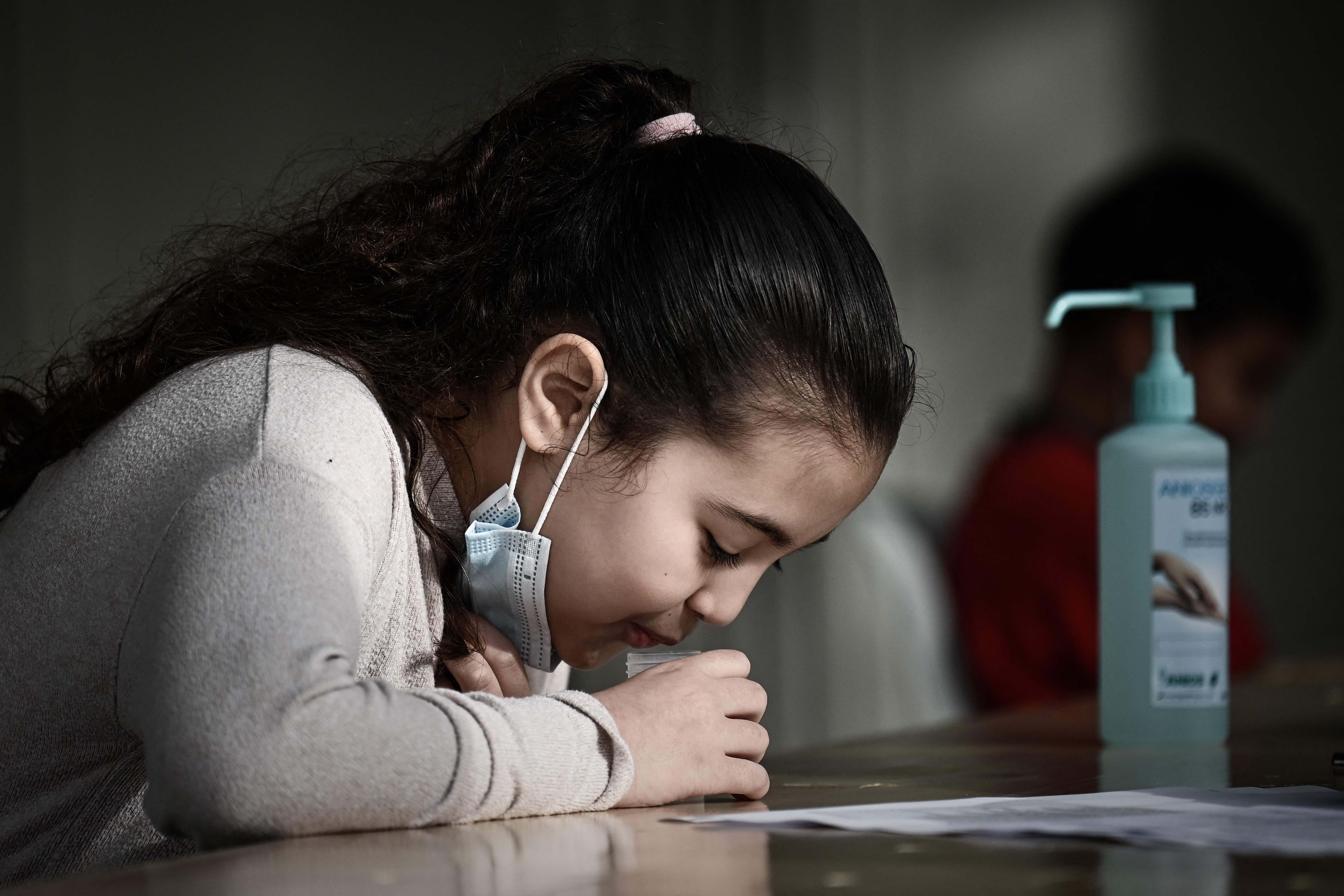 Seorang siswi memberikan sampel selama tes air liur untuk covid-19 di sekolah dasar di Eysines, Prancis, beberapa waktu lalu.