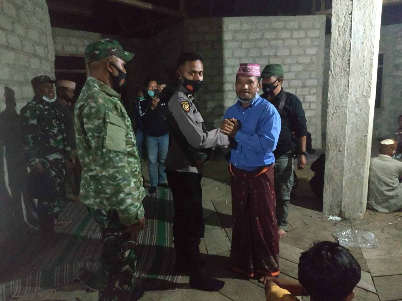 Yosef Sudirman Bagu (kanan) bersalaman dengan polisi dan tentara usai ritual adat perdamaian di Mbaru Gendang Siri Mese. 
