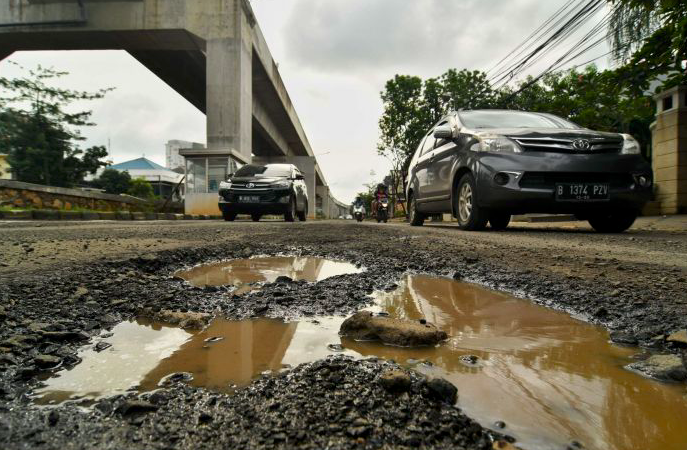 Sejumlah kendaraan memperlambat laju kendaraannya untuk menghindari lubang di kawasan Kelapa Gading, Jakarta Utara.