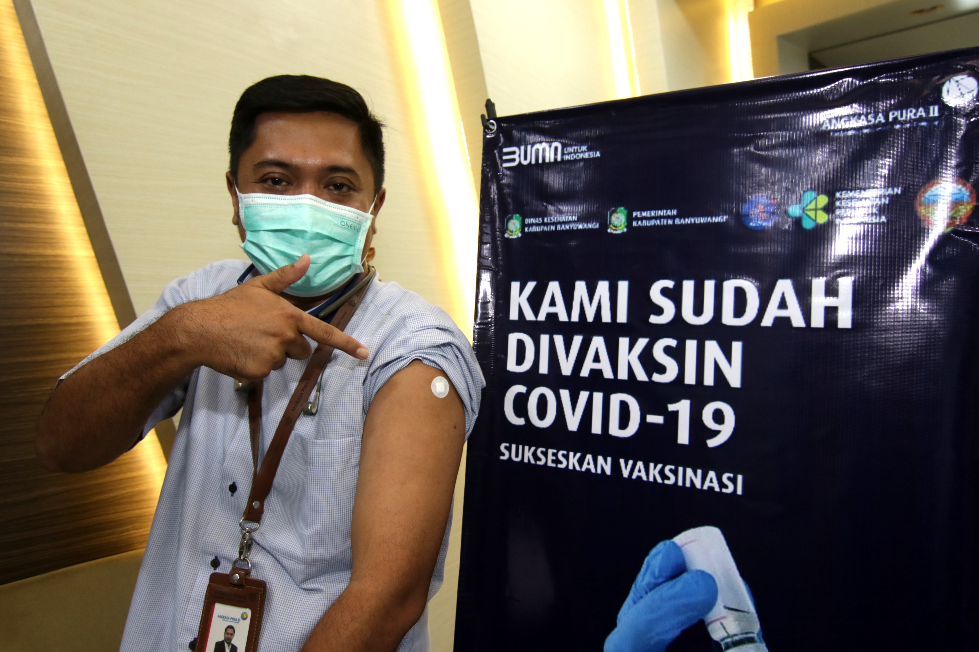 Petugas Angkasa Pura II menunjukkan bekas vaksinasi di Bandara Banyuwangi, Jawa Timur, Jumat (26/3).