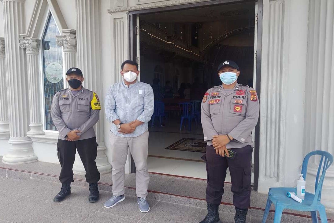 Tiga anggota Polres Tanjung Jabung Barat, Jambi, menjaga pintu masuk gereja di Kota Kuala Tungkal, Minggu (28/3).