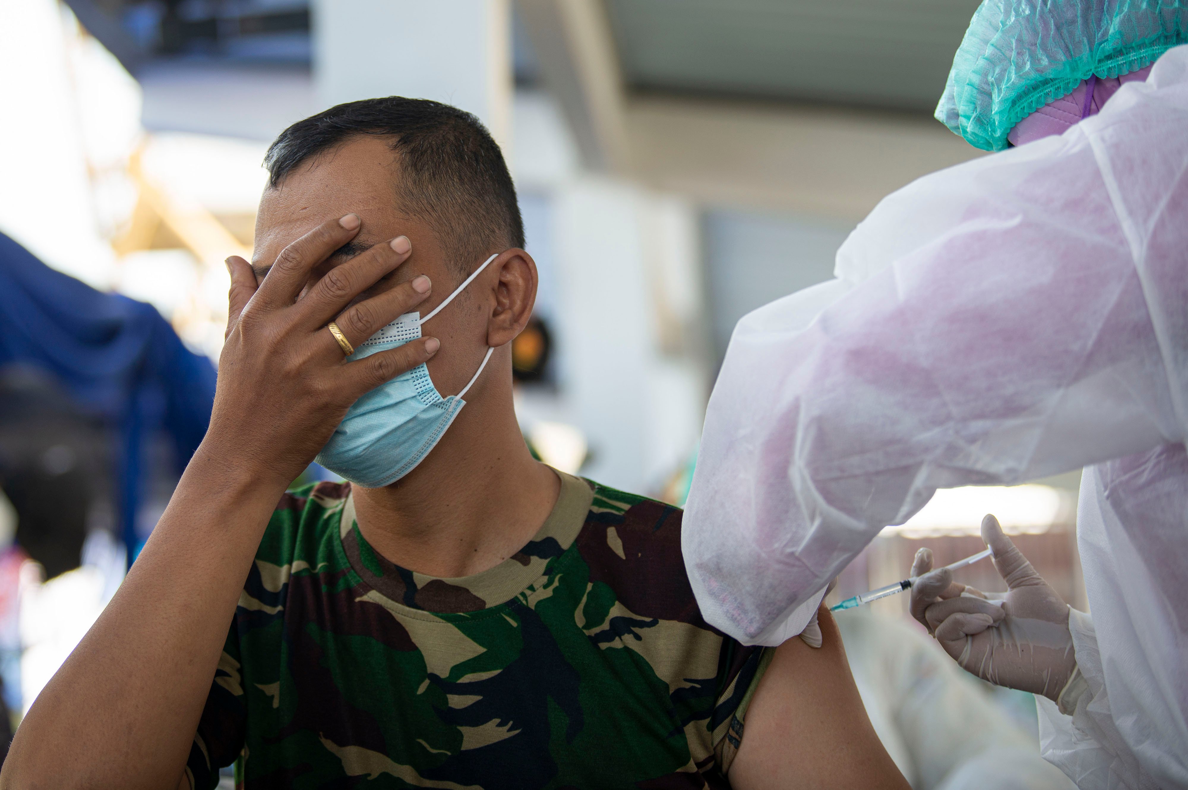 Seorang prajurit TNI AL menutup mata saat disuntik vaksin covid-19.