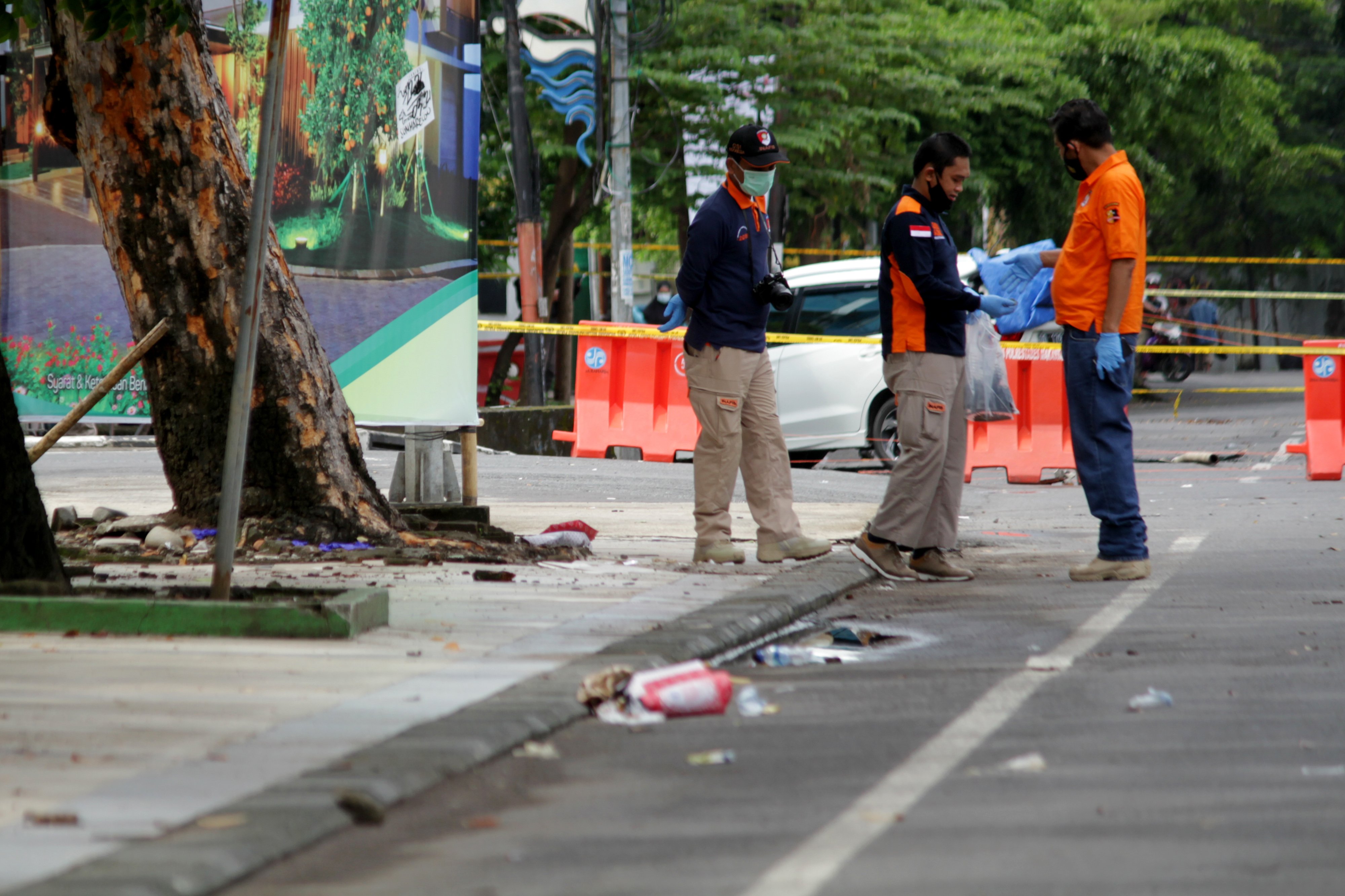 PASCALEDAKAN BOM DI MAKASSAR: Anggota polisi mengumpulkan sisa serpihan ledakan bom bunuh diri di depan Gereja Katedral Makassar, Sulsel