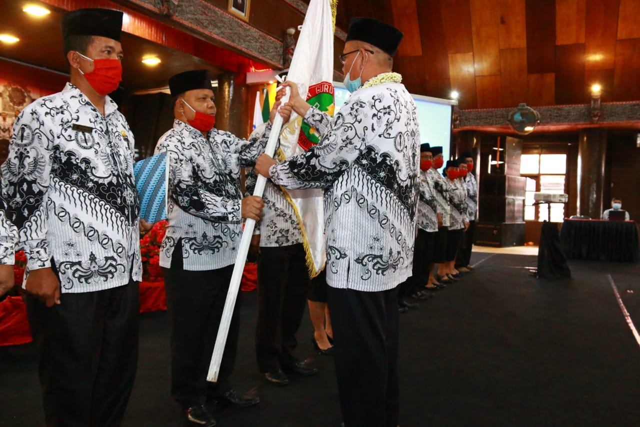Ketua PGRI Taput Alfa Simanjuntak (kiri) menerima pataka dari Ketua PGRI Sumatra Utara Abdul Rahman Siregar.