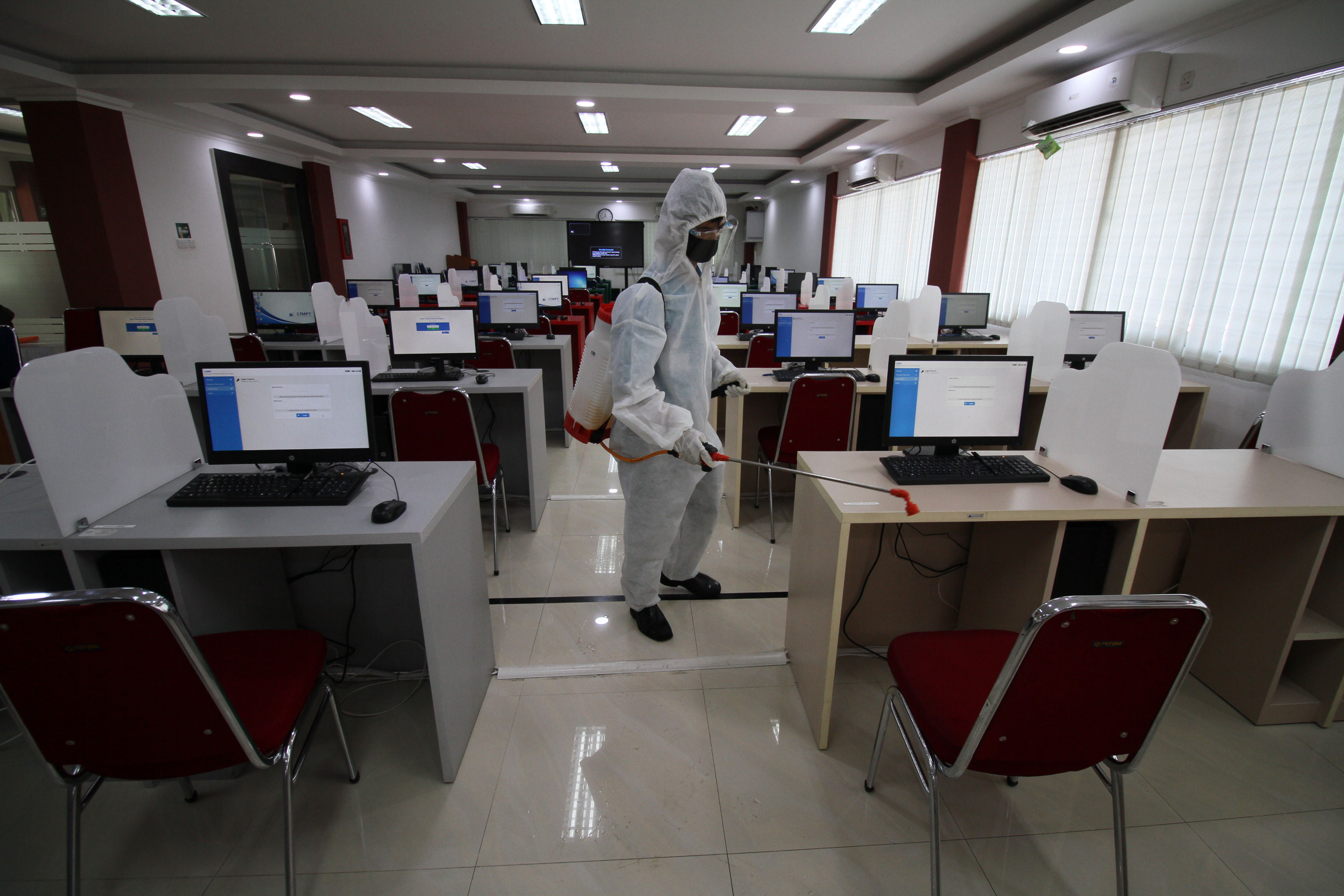Petugas menyemprotkan disinfektan ke komputer yang digunakan untuk UTBK