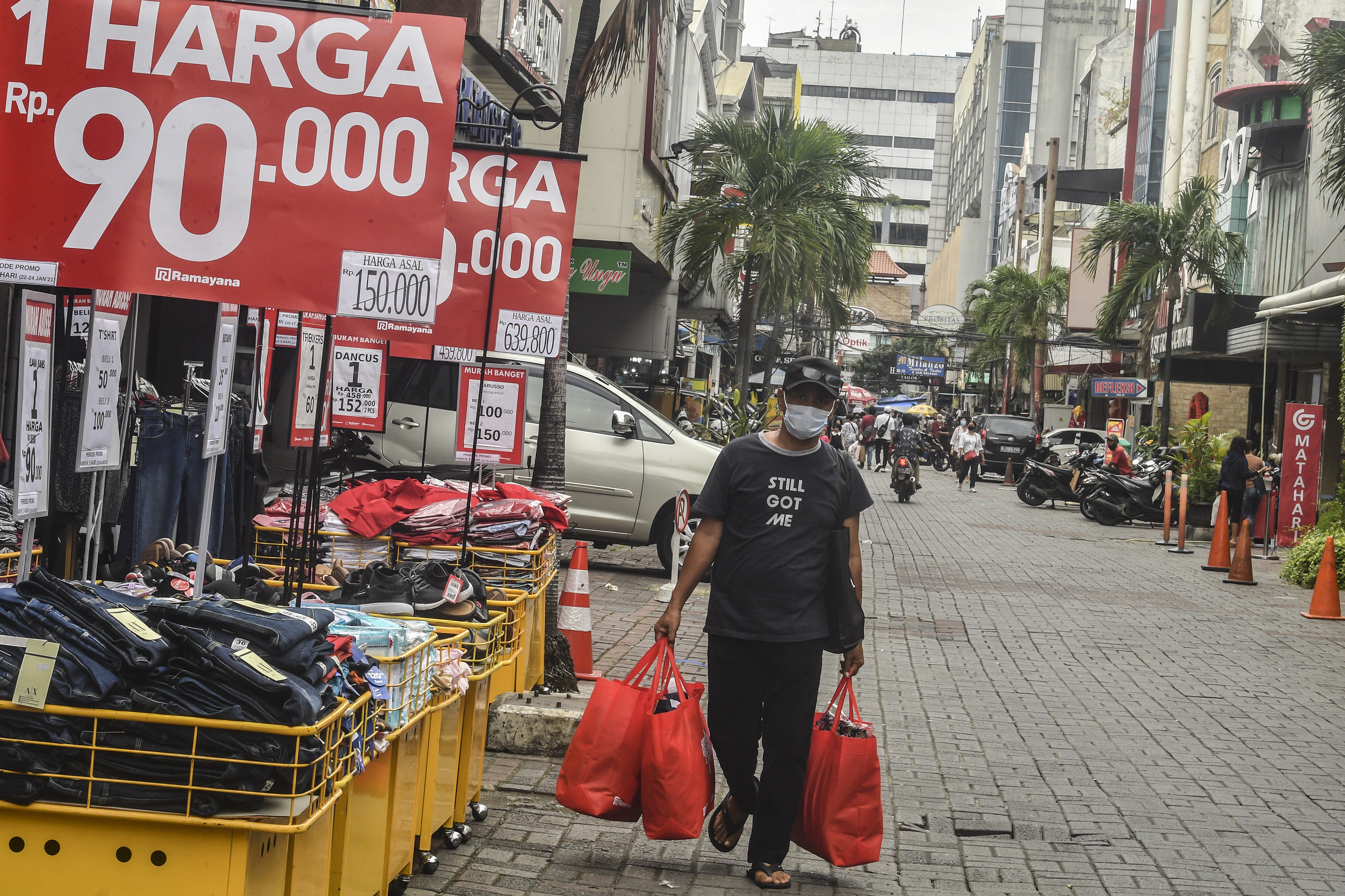 Warga berjalan membawa belanjaannya di kawasan Pasar Baru, Jakarta.
