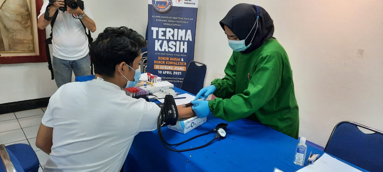 Seorang tenaga kesehatan (kanan) tengah mengambil sampel darah pendonor.