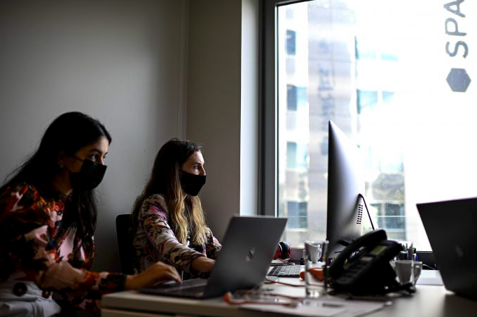  Dua orang perempuan tengah bekerja di sebuah kantor di Paris, Prancis dengan mengenakan masker.