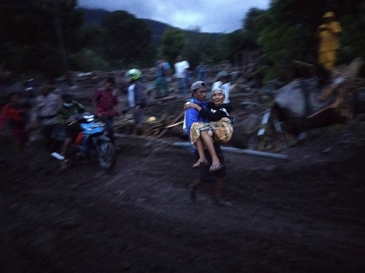 Seorang perempuan tua digendong warga usai banjir bandang melanda Desa Amakaka, Ile Ape, Lembata, NTTm Sabtu (3/4). 