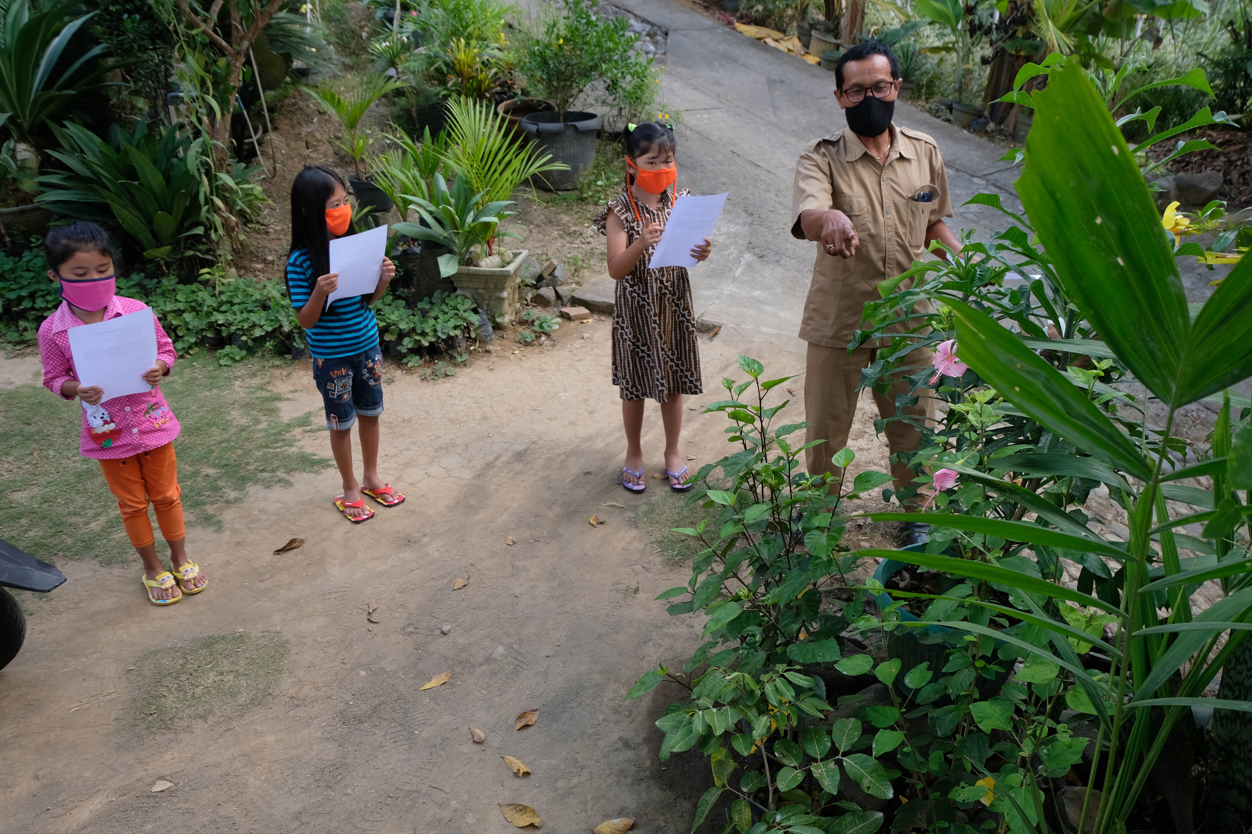 Guru SD Kanisius Kenalan Henricus Suroto (kanan) mengajar muridnya di halaman rumah warga di Dusun Plengan, Kalibawang, Kulonprogo, DIY