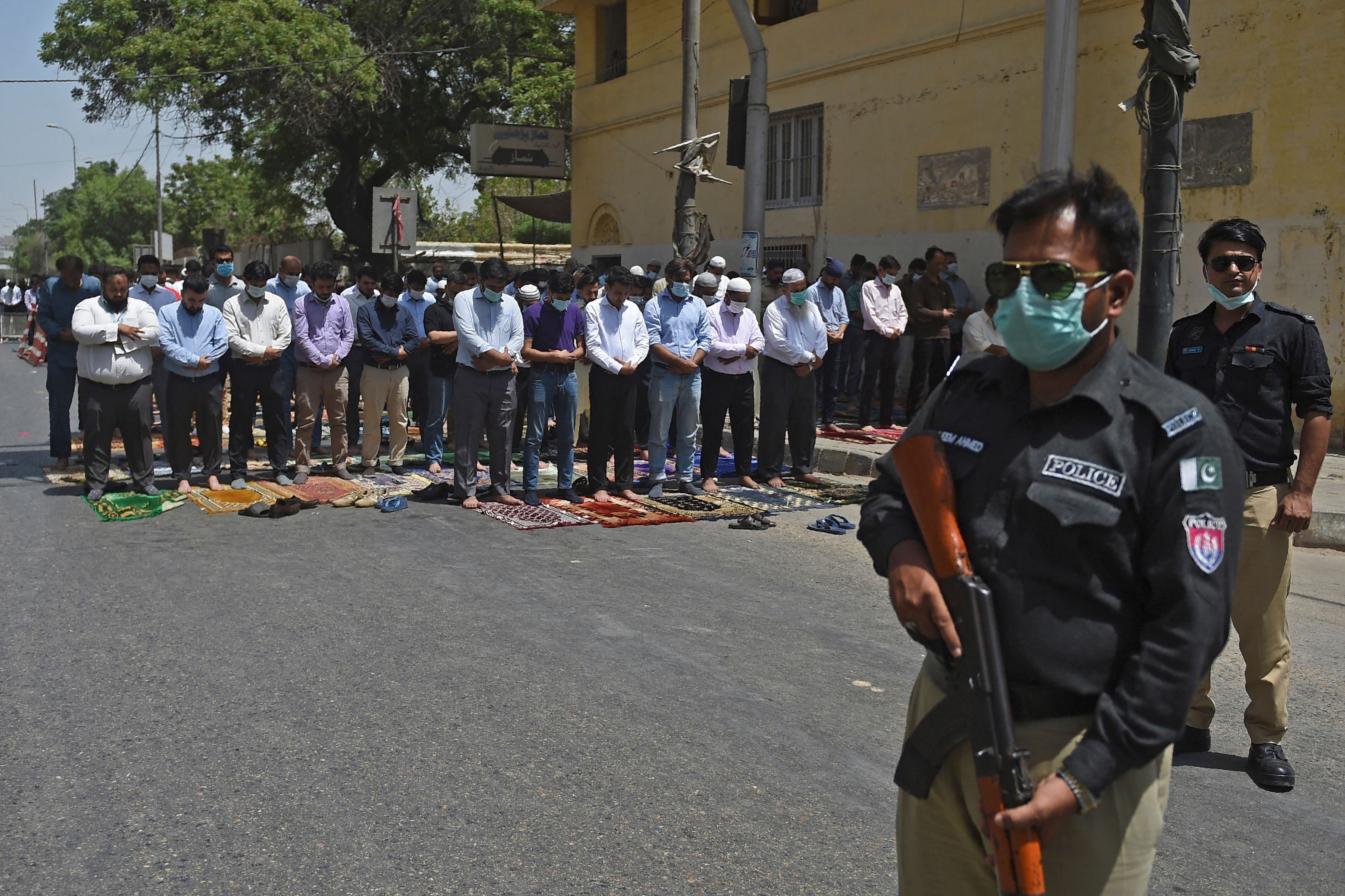 Seorang polisi berjaga-jaga saat jemaah salat Jumat di jalan selama bulan suci Ramadan di Karachi, Jumat (23/4).