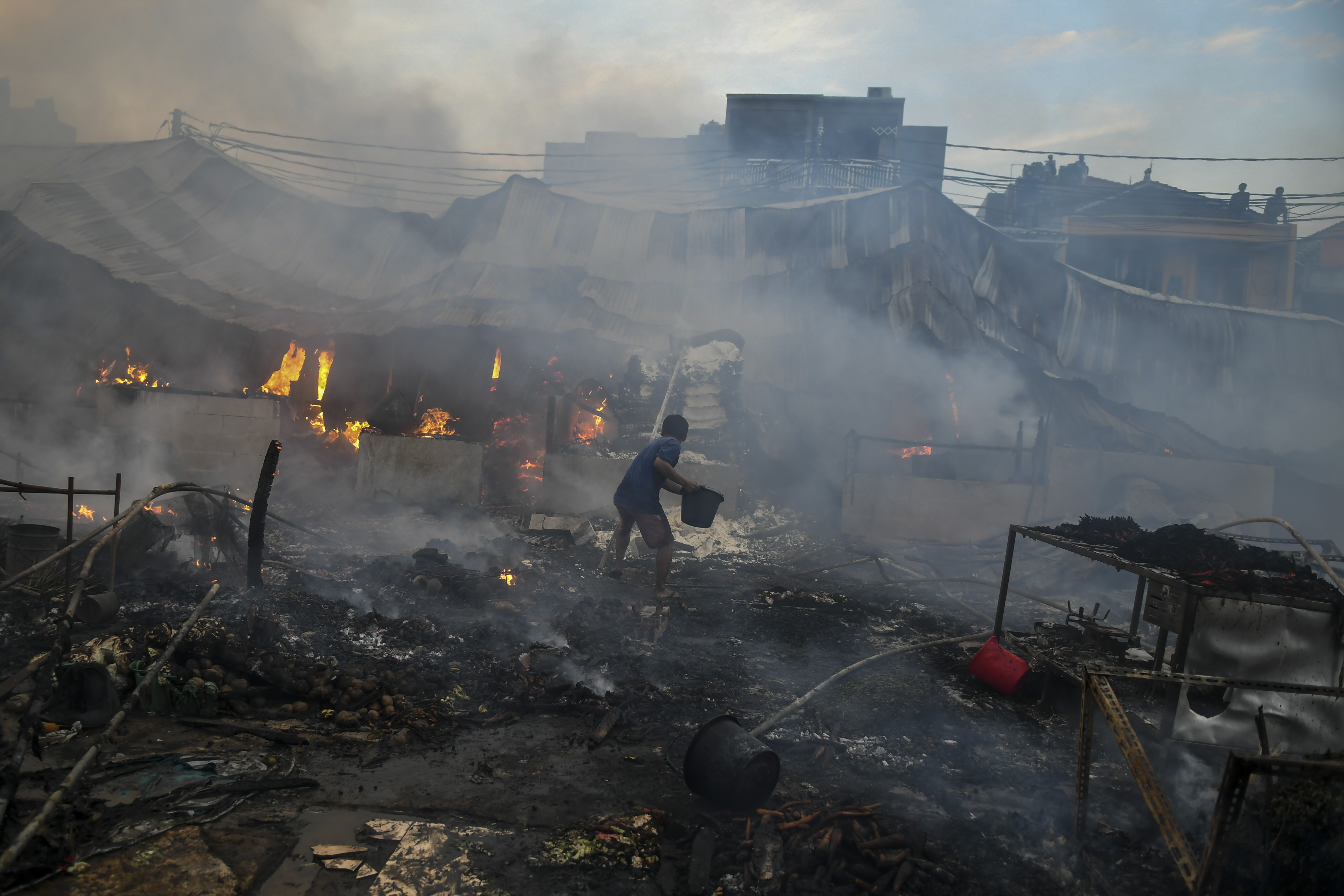 Warga memadamkan api yang membakar Pasar Lontar atau Pasar Kambing di Jalan Sabeni, Tanah Abang, Jakarta, hari ini.