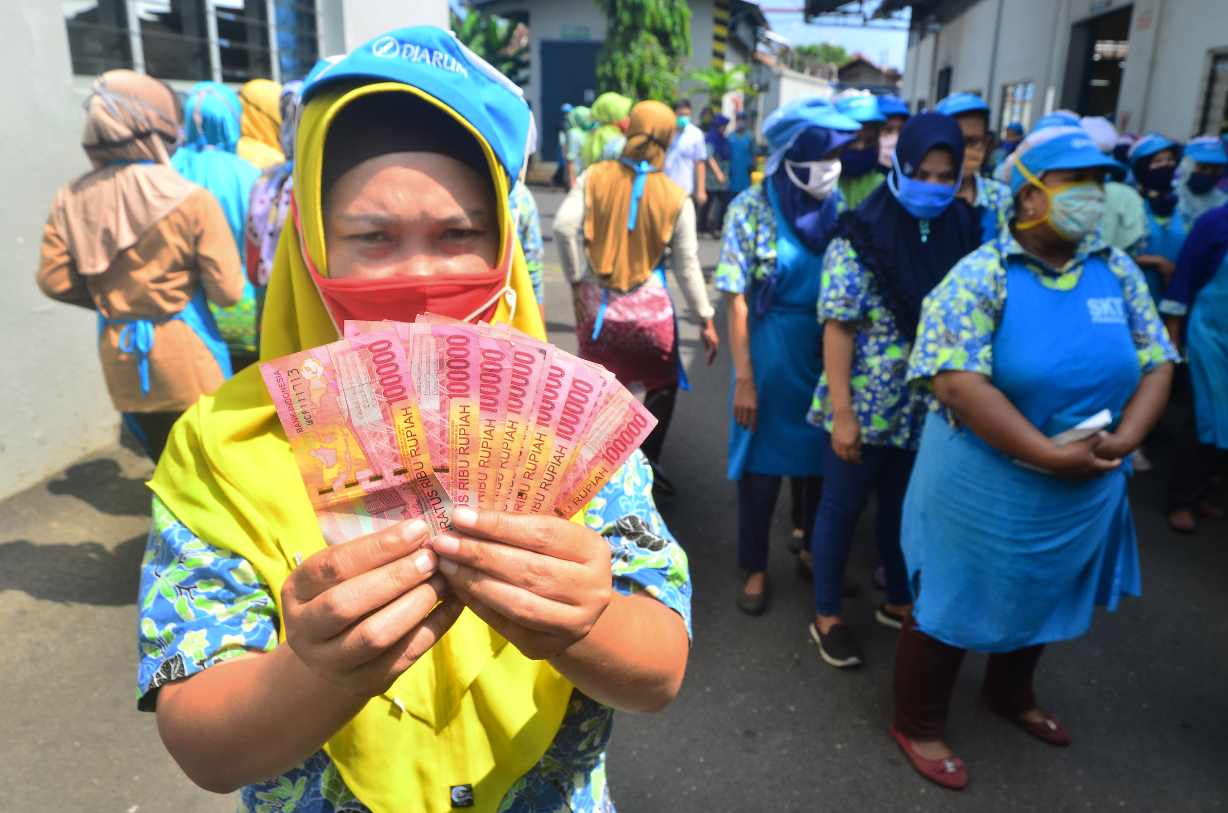 Pekerja menunjukkan uang Tunjangan Hari Raya (THR)