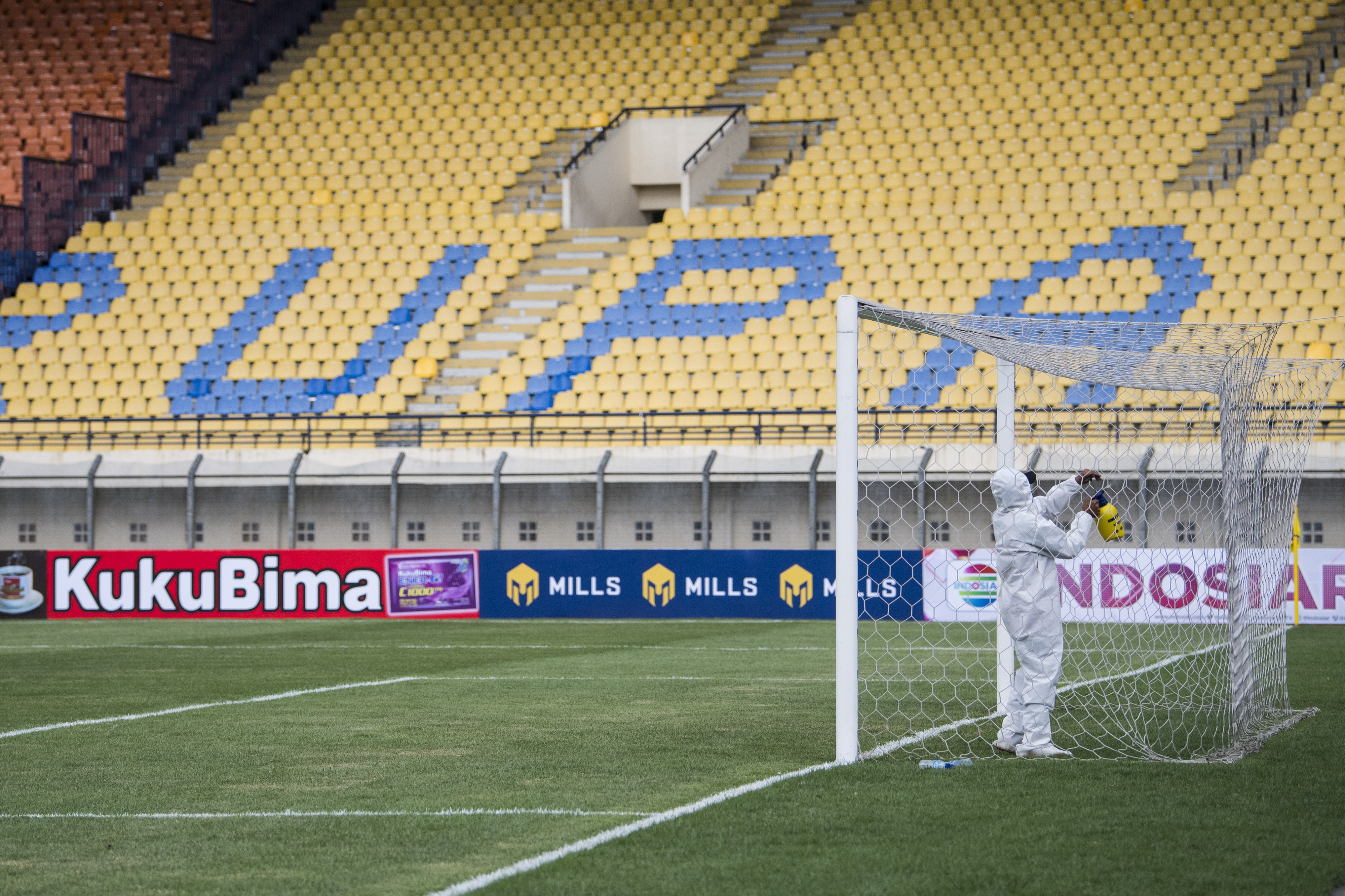 Petugas menyemprotkan cairan disinfektan ke tiang gawang di Stadion Si Jalak Harupat, Jawa Barat, Selasa (23/3).
