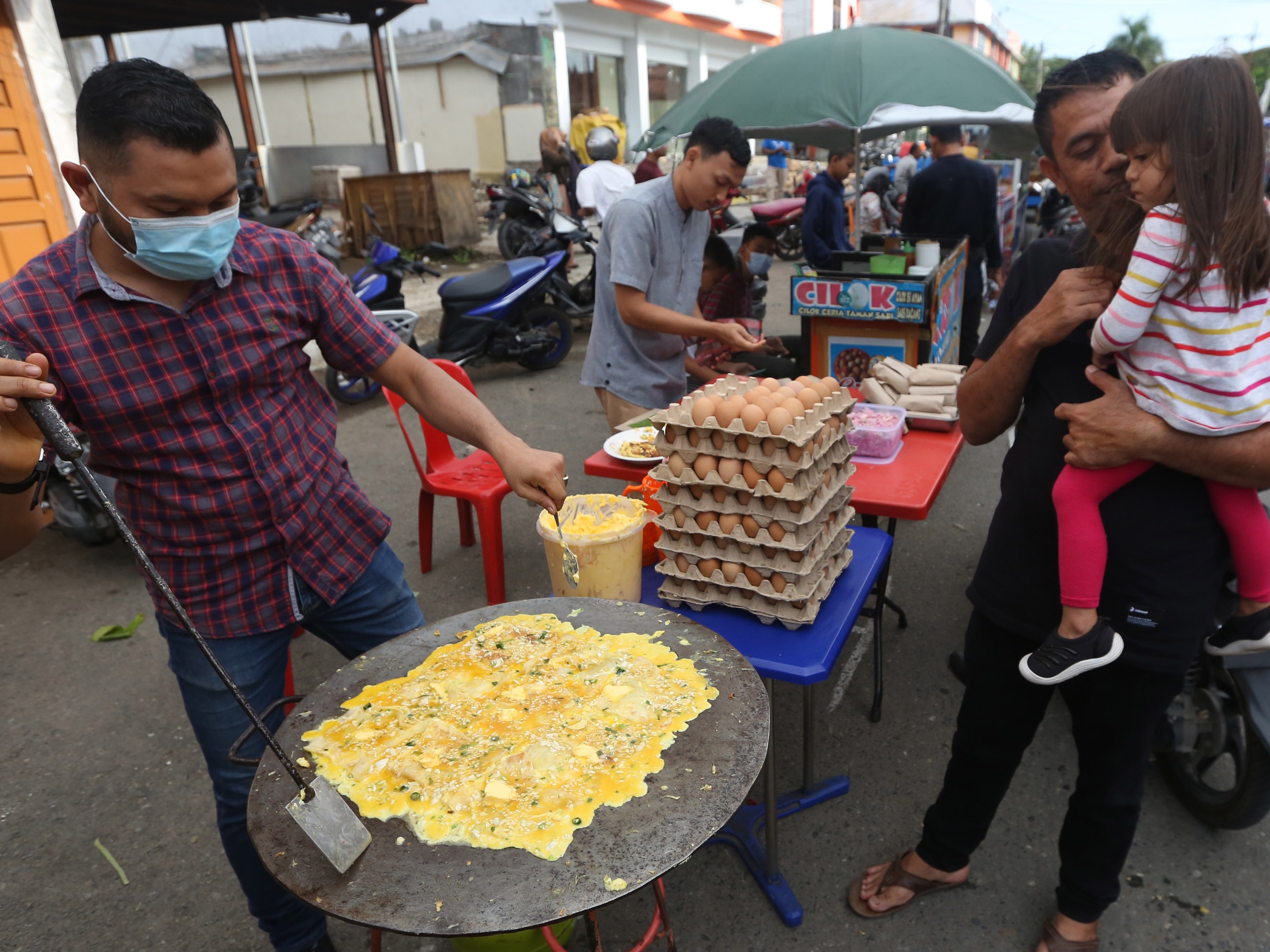 Pedagang musiman (kiri) memasak martabak Aceh untuk menu berbuka puasa yang dijajakan di pasar takjil Ramadan, Banda Aceh, Rabu (14/4).