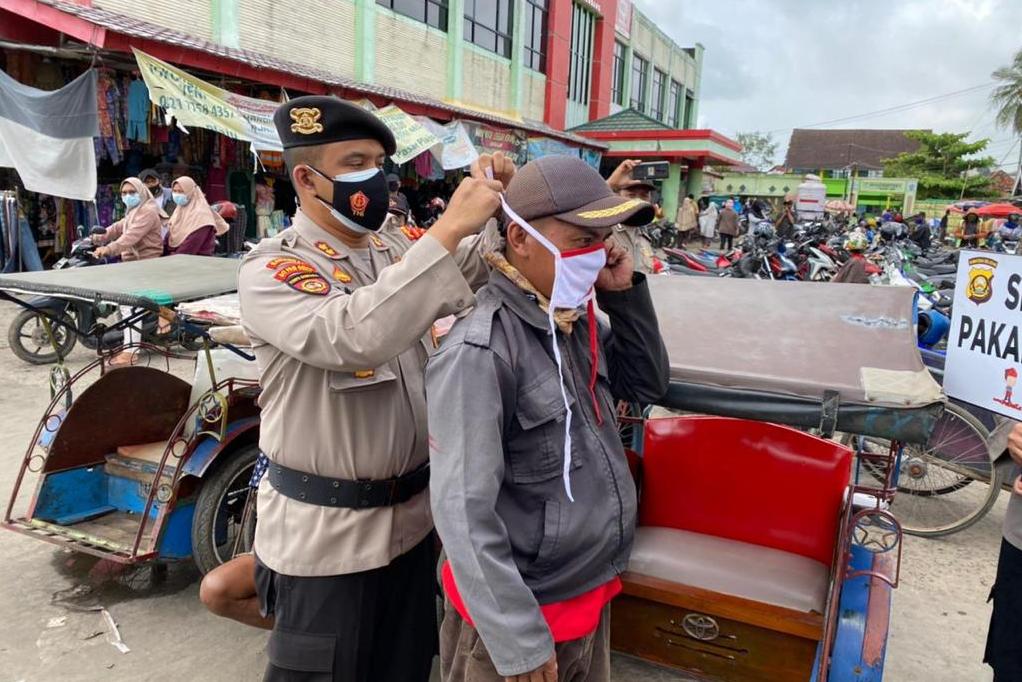 Personil Polda Sumsel dan TNI mengedukasi pentingnya protokol kesehatan dan membagikan masker di Pasar Modern Plaju Palembang.