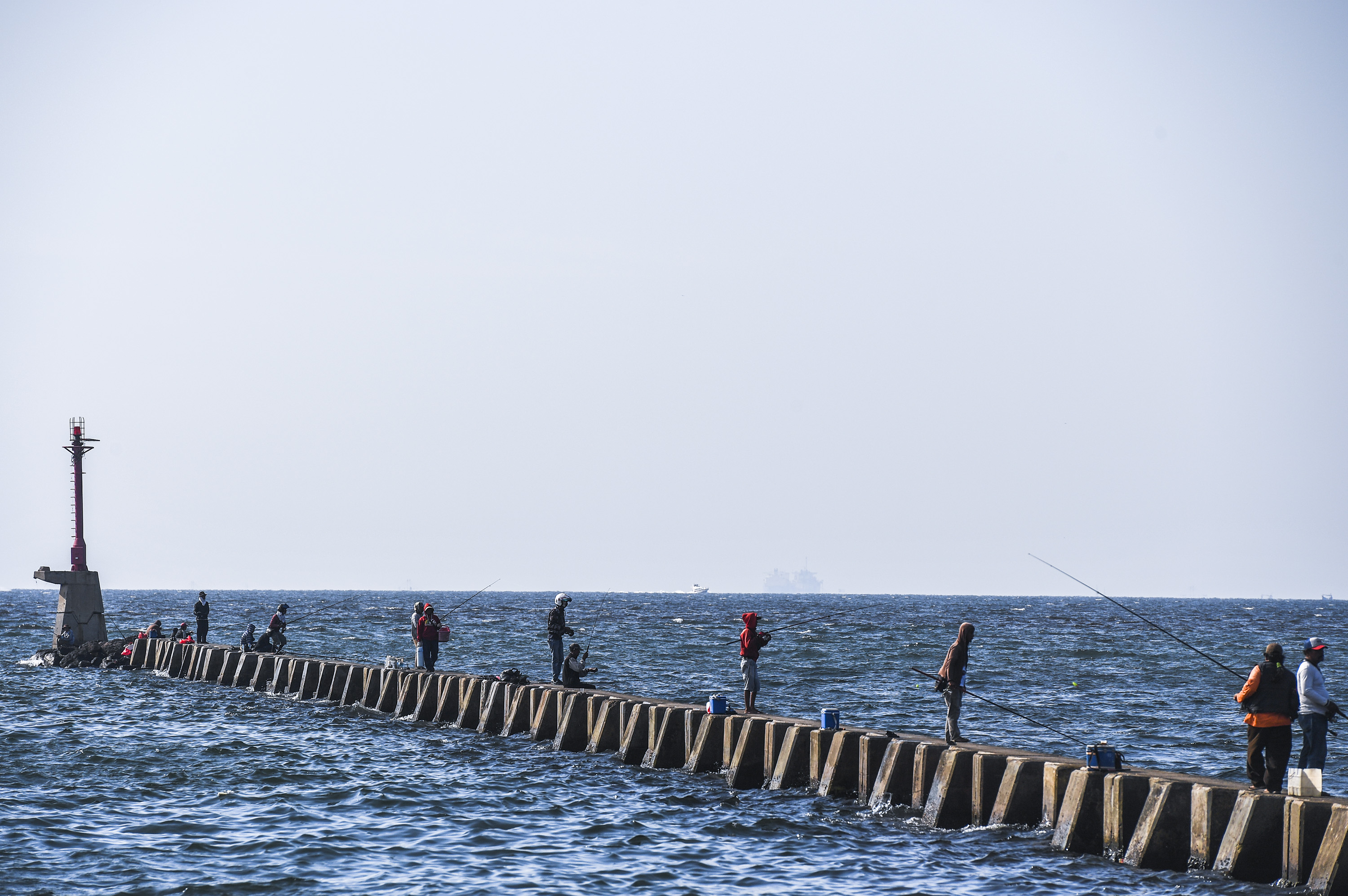 Cuaca cerah di pesisir Jakarta dimanfaatkan warga untuk memancing ikan di perairan Jakarta. 