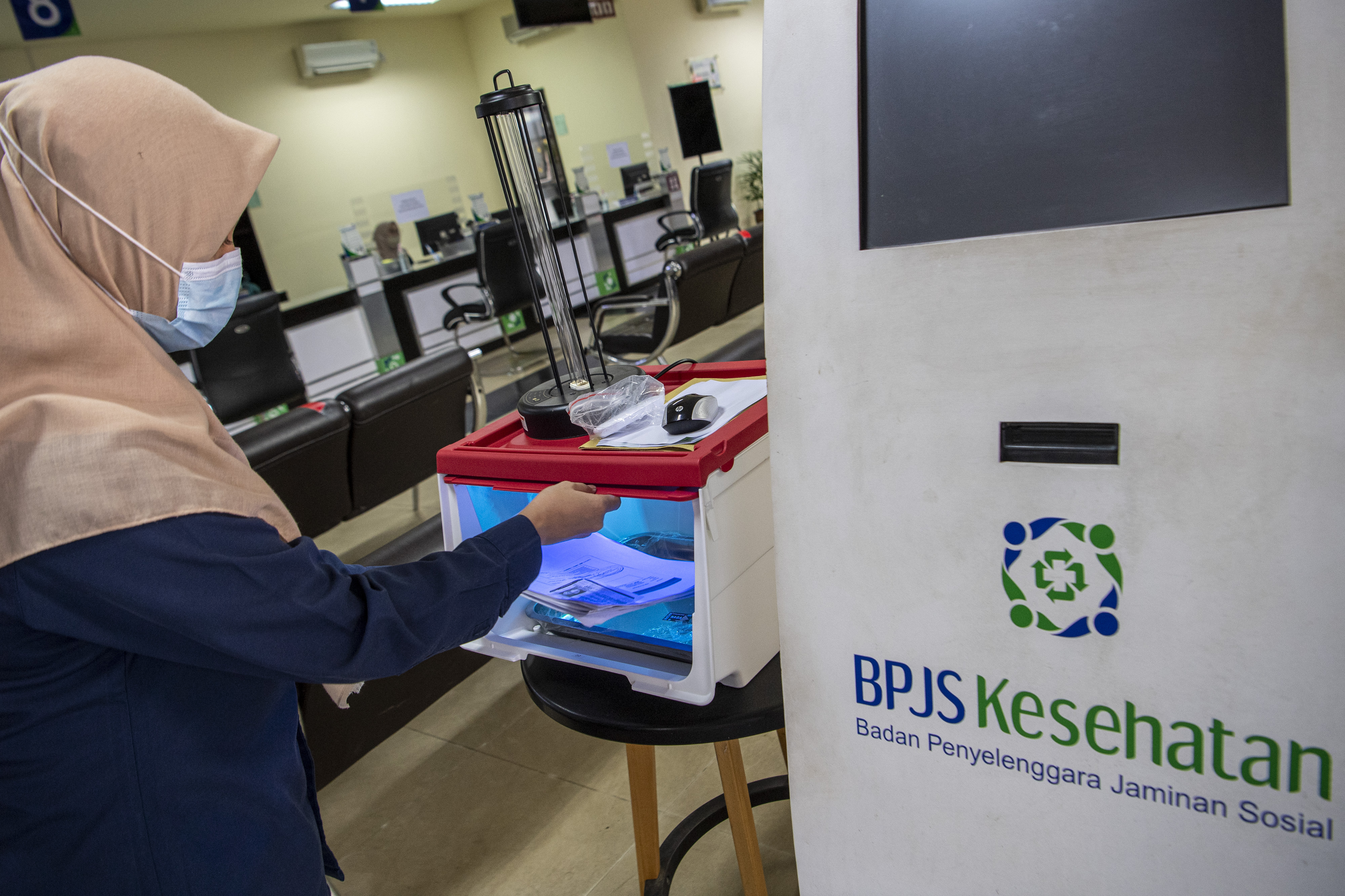 Ilustrasi petugas saat mengambil dokumen milik peserta BPJS Kesehatan yang disterilisasi.