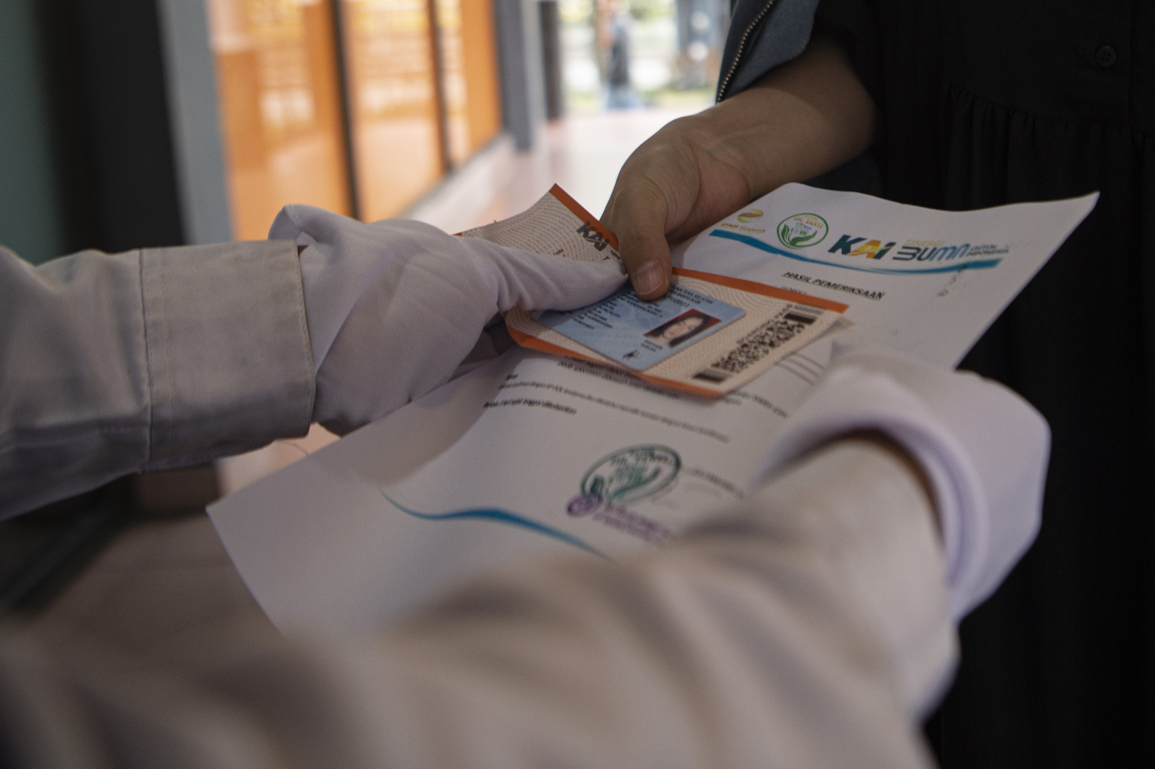 Petugas kesehatan menyerahkan surat keterangan hasil pemeriksaan tes usap antigen