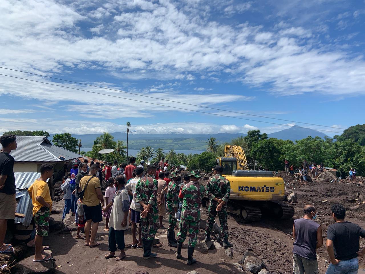 Sejumlah warga dan tentara tengah mengawasi eskavator. 