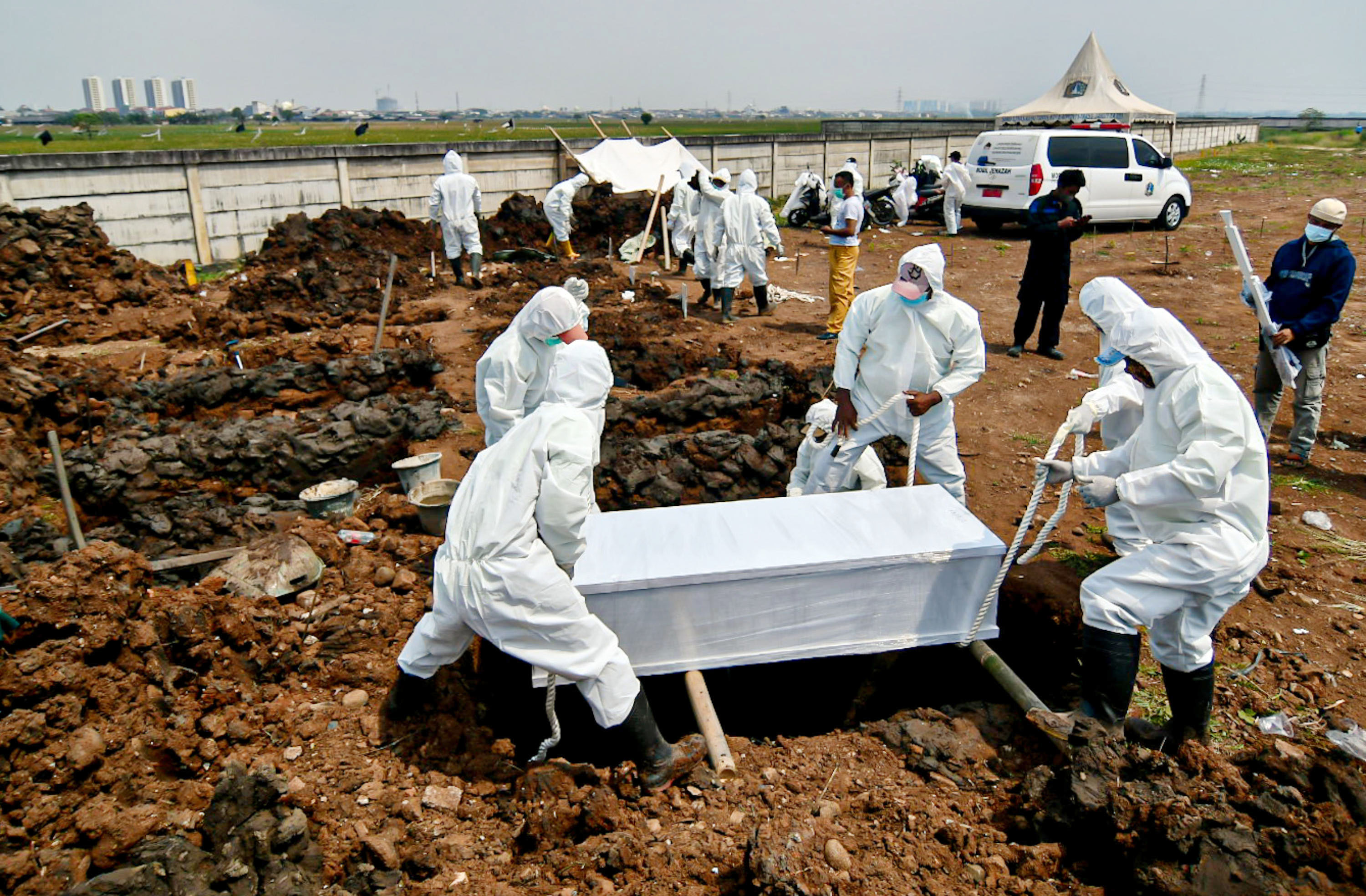 Petugas menggunakan baju pelindung saat memakamkan jenazah pasien terkonfirmasi Covid-19 di Tempat Pemakaman Umum (TPU) Rorotan, Jakarta.