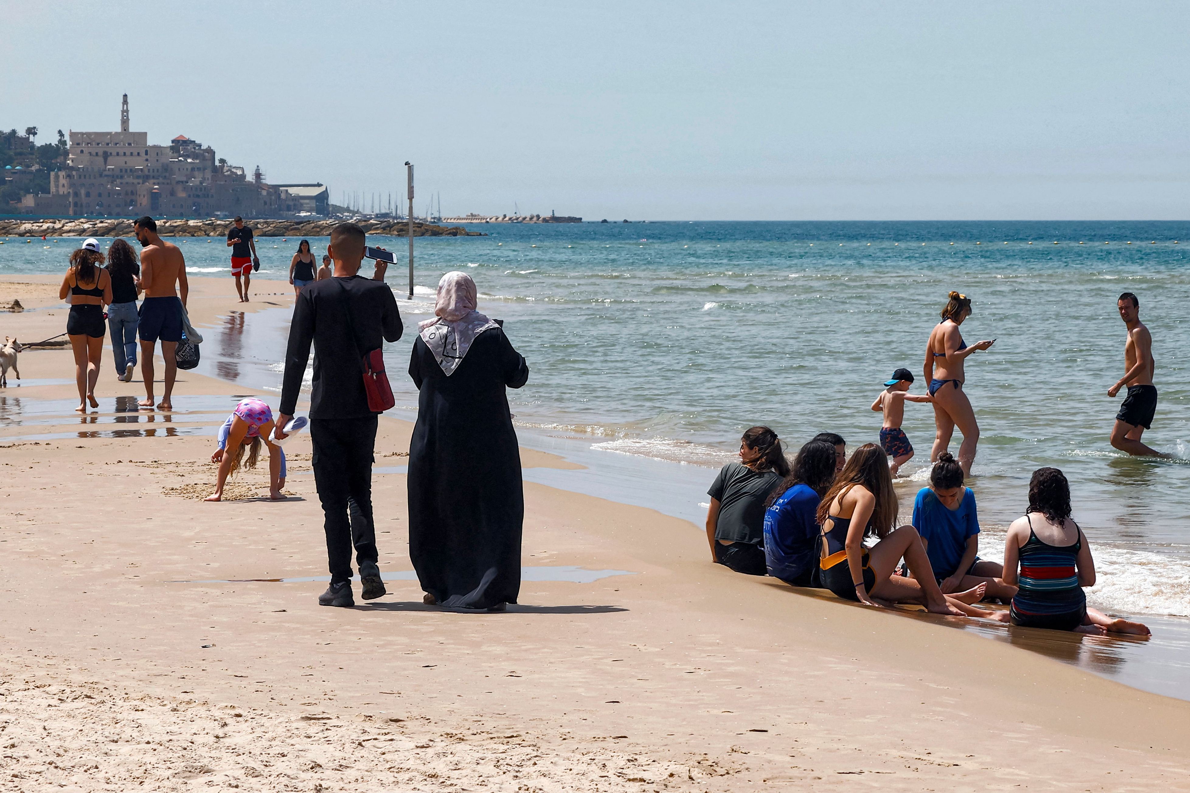 Orang-orang berjalan dan duduk di sepanjang pantai kota pesisir Mediterania di Israel, Tel Aviv, Rabu (7/4).