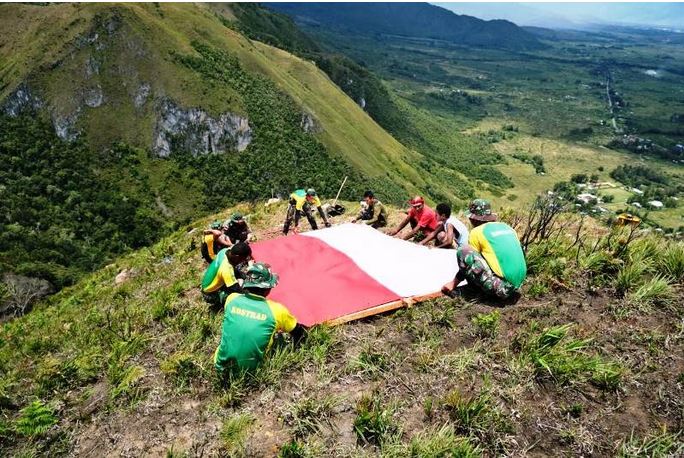 Kepala Suku Kurulu Mabel bersama prajurit Satgas TNI Yonif PR 432 membentangkan Bendera Merah Putih di Puncak Gunung Bagarek.