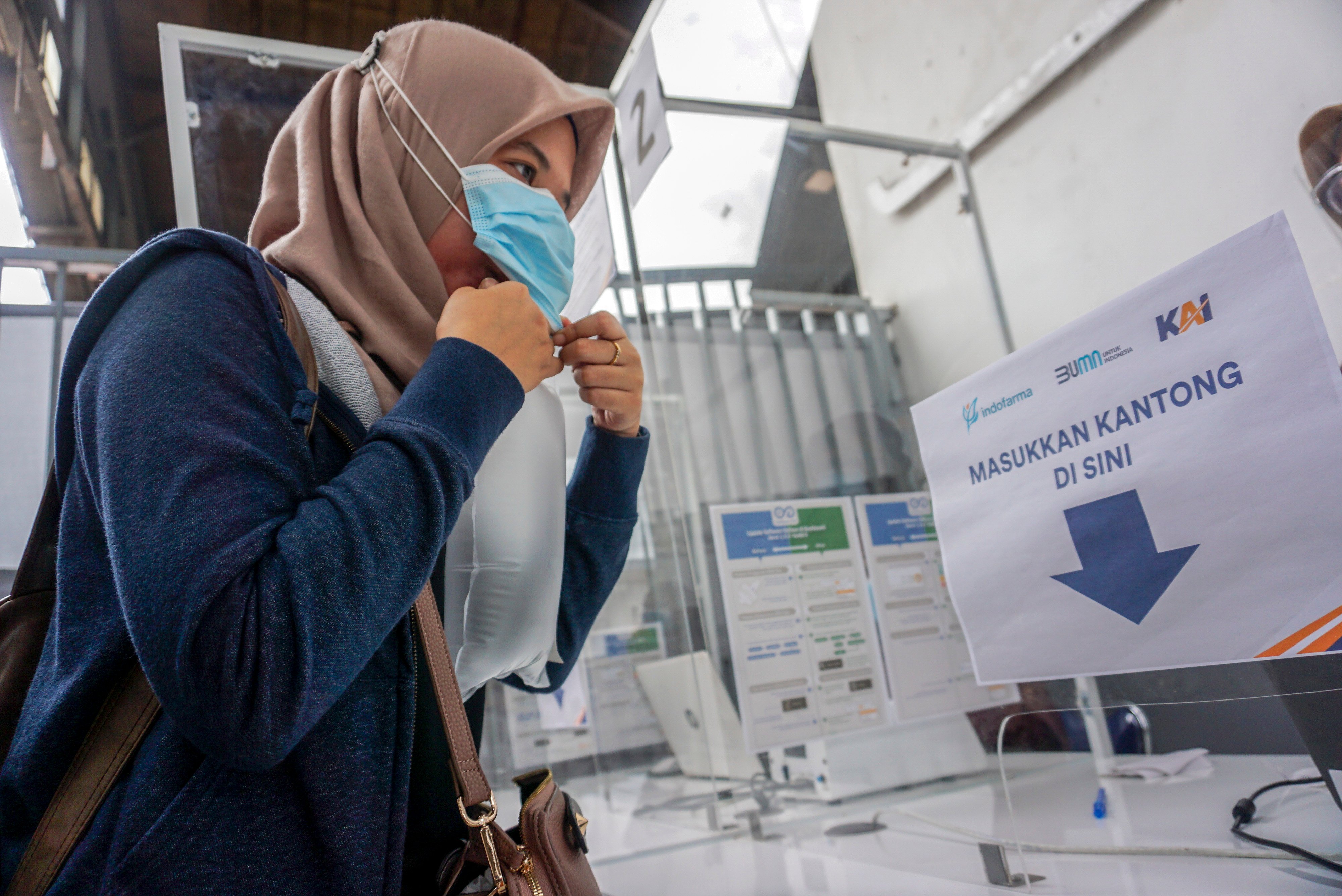 Calon penumpang kereta api meniupkan nafas ke kantong plastik untuk tes deteksi COVID-19 metode GeNose C19 di Stasiun Pekalongan.