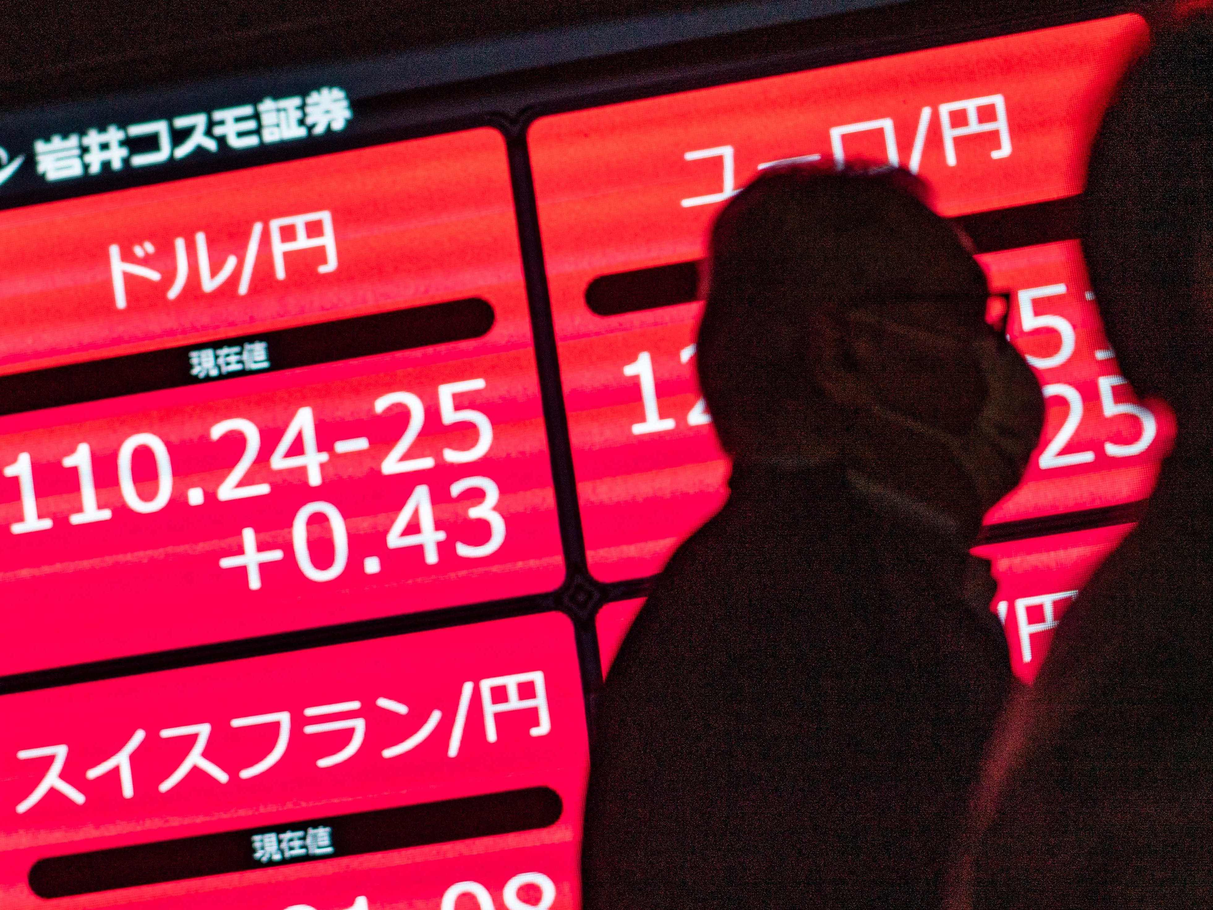 Orang-orang berjalan melewati papan elektronik yang menampilkan nilai tukar yen Jepang terhadap dolar AS di Tokyo, Jepang.