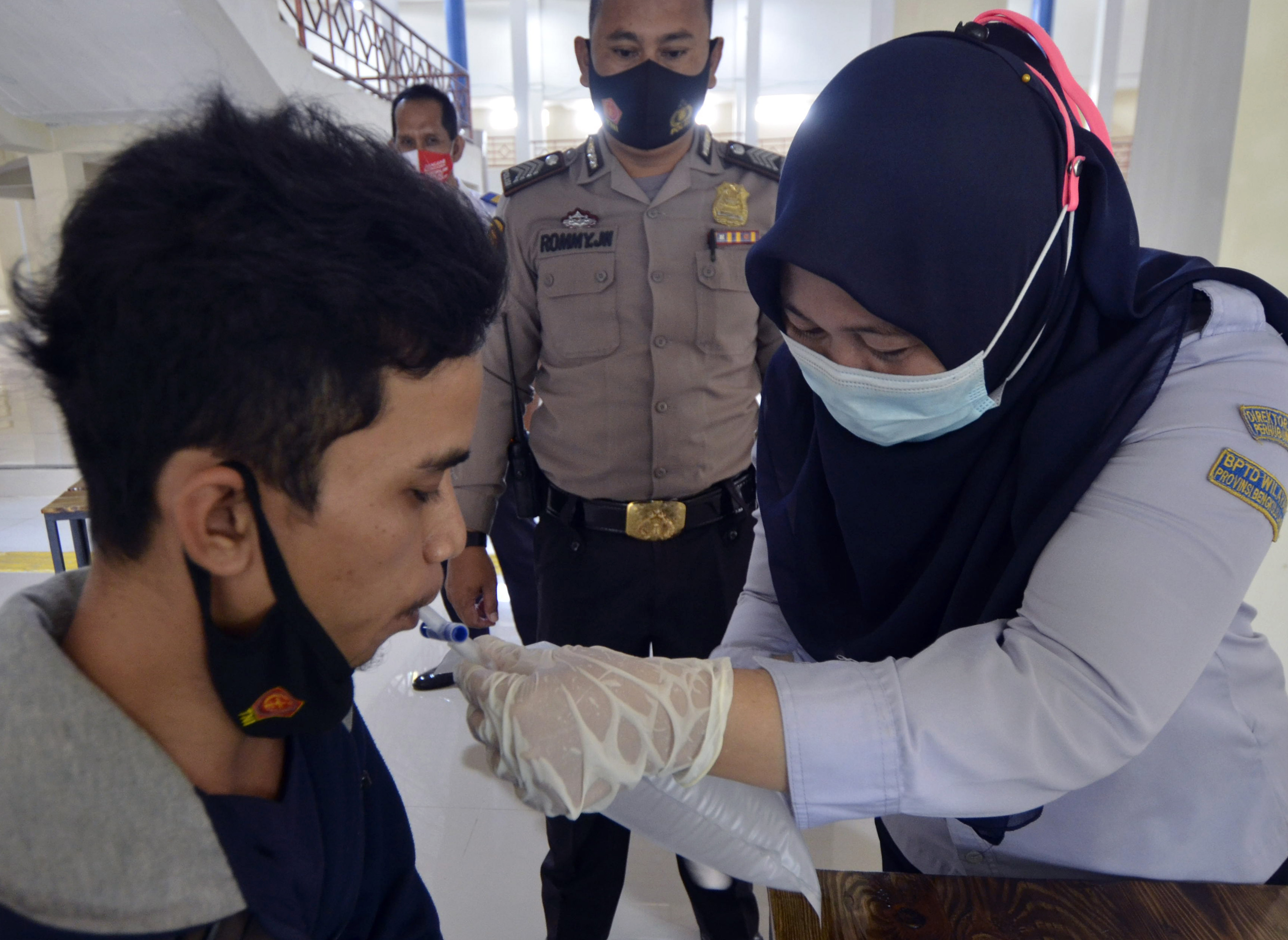 Calon penumpang meniupkan nafas ke dalam kantong untuk dites menggunakan alat GeNose C19 di Terminal Type A Rajabasa, Bandar Lampung.