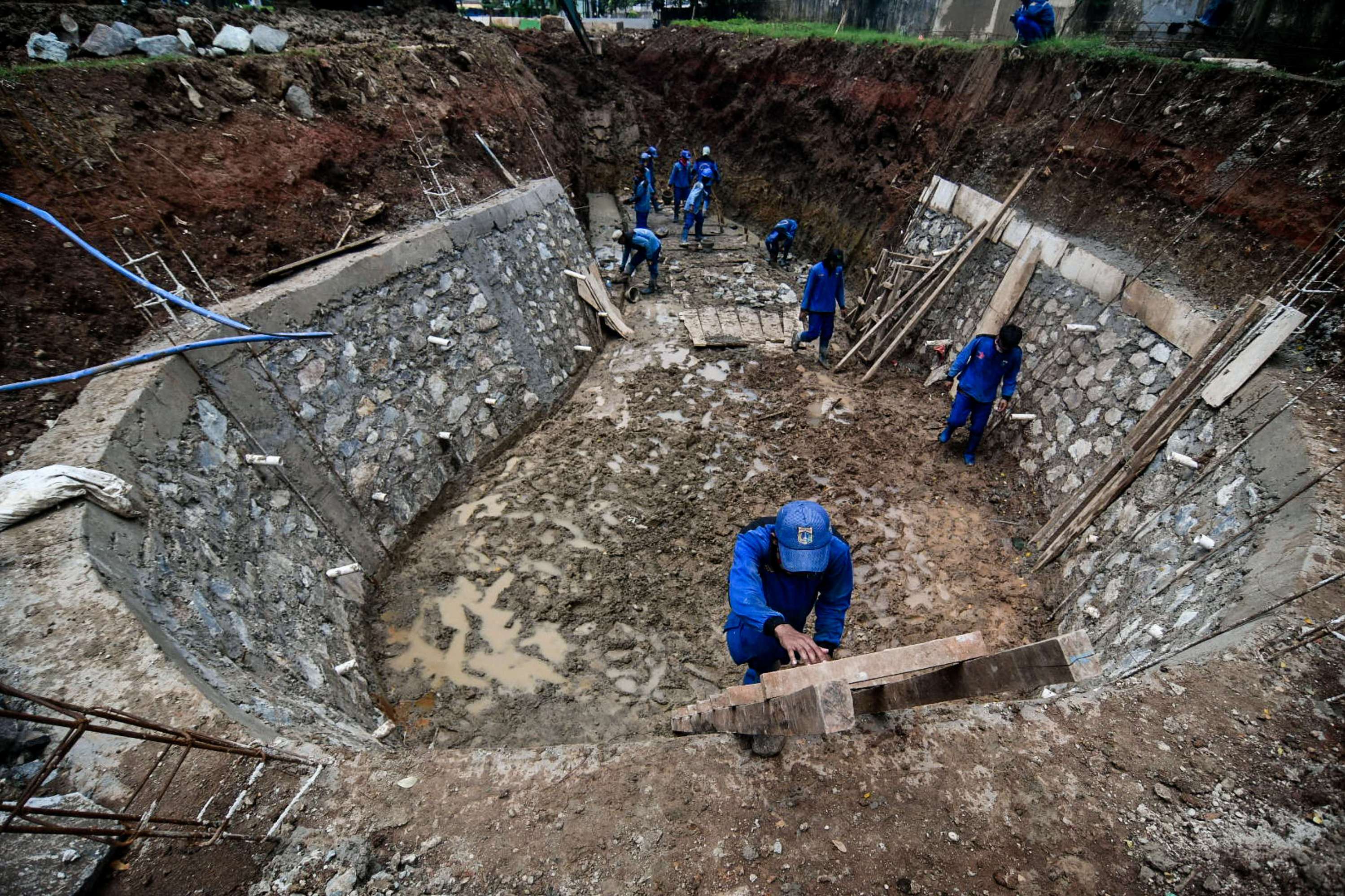 Petugas Suku Dinas Sumber Daya Air Jakarta Pusat mengerjakan pembuatan embung di Jalan Letjend Suprapto, Sumur Batu, Kemayoran.