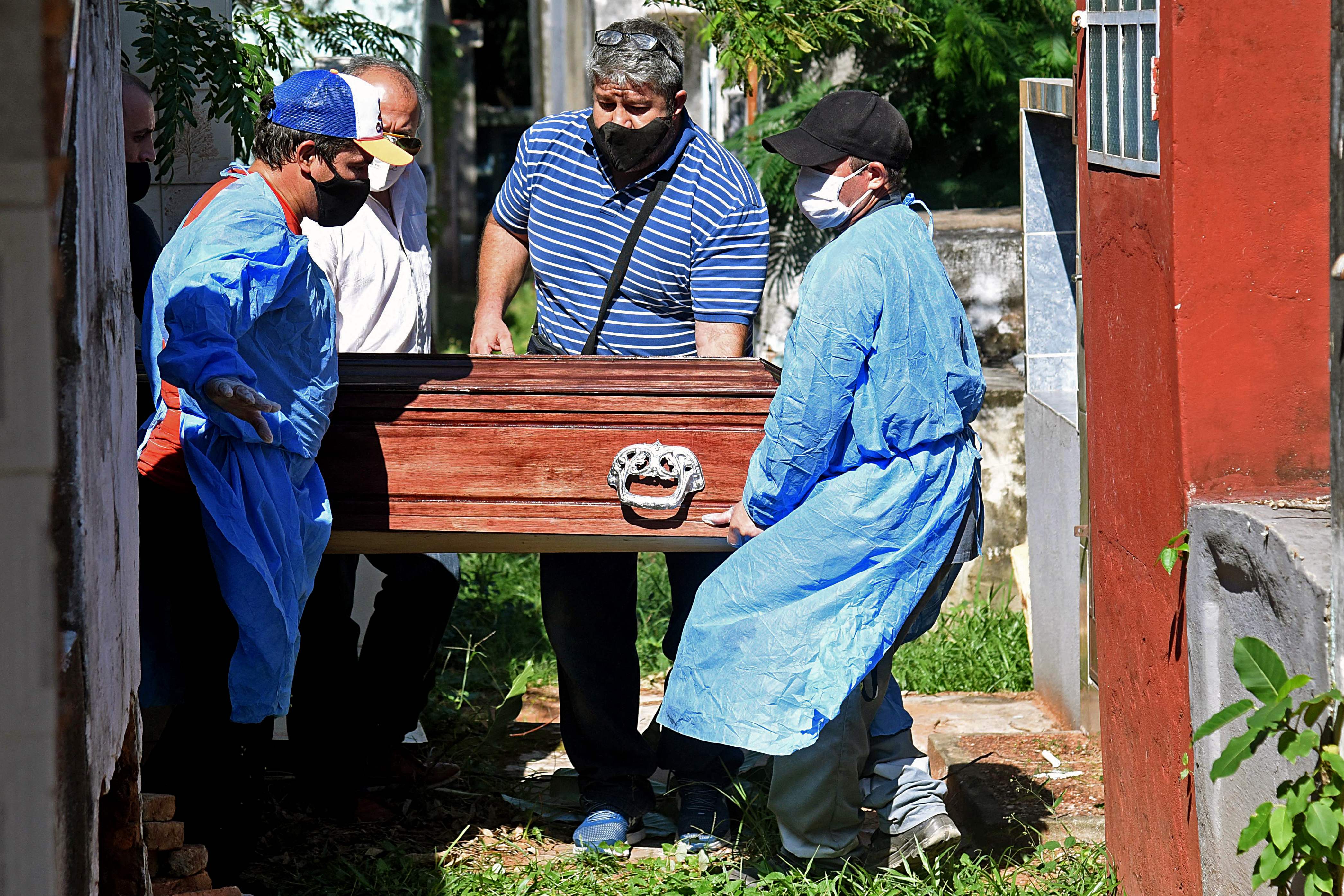 Petugas membawa peti jenazah berisi jenazah pasien covid-19 di taman makam Cementerio del Sur di Asuncion, Paraguay.